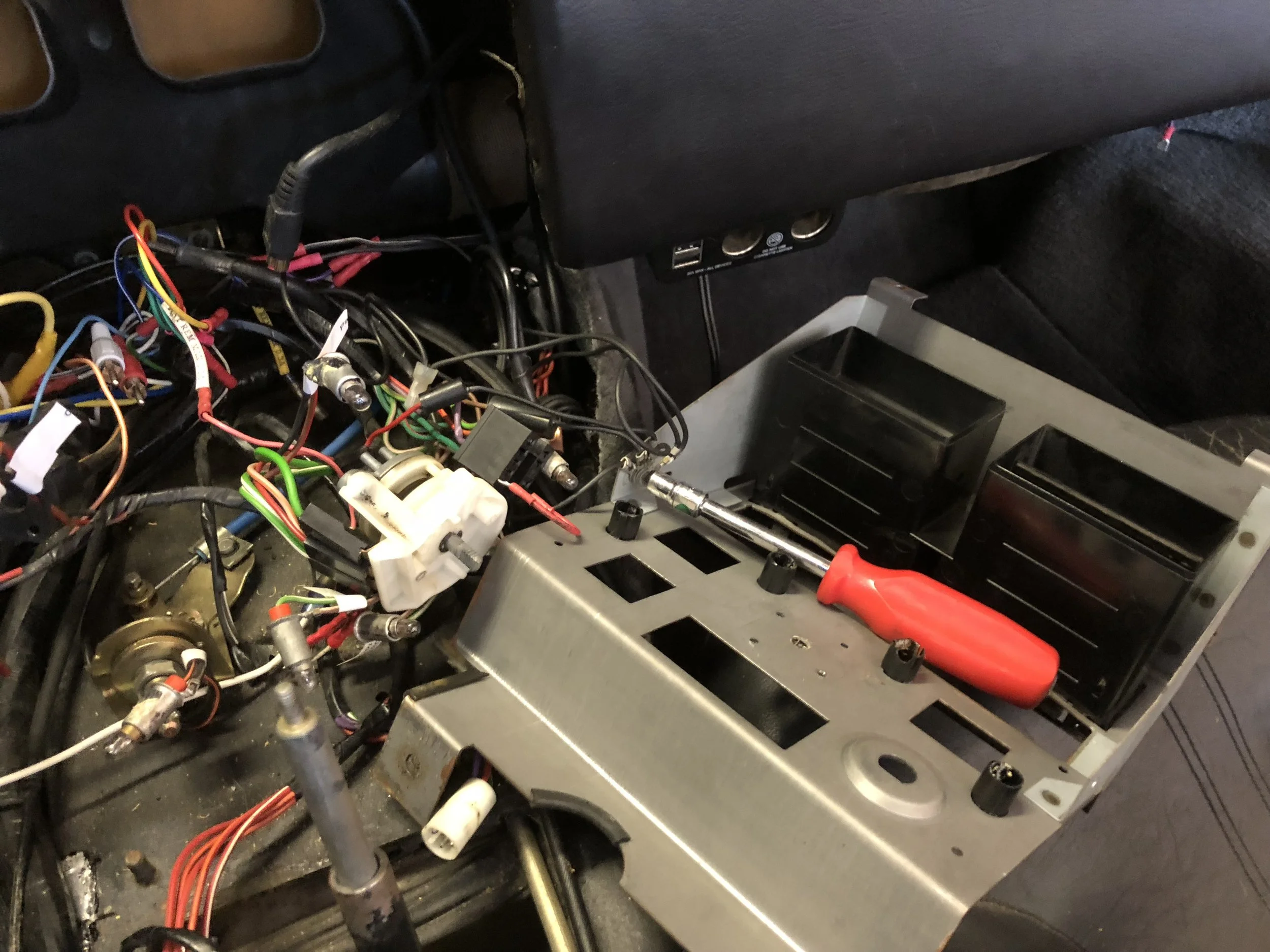 The red-handled bit driver is on the ground bundle that needs too be disconnected to remove the center stack frame.