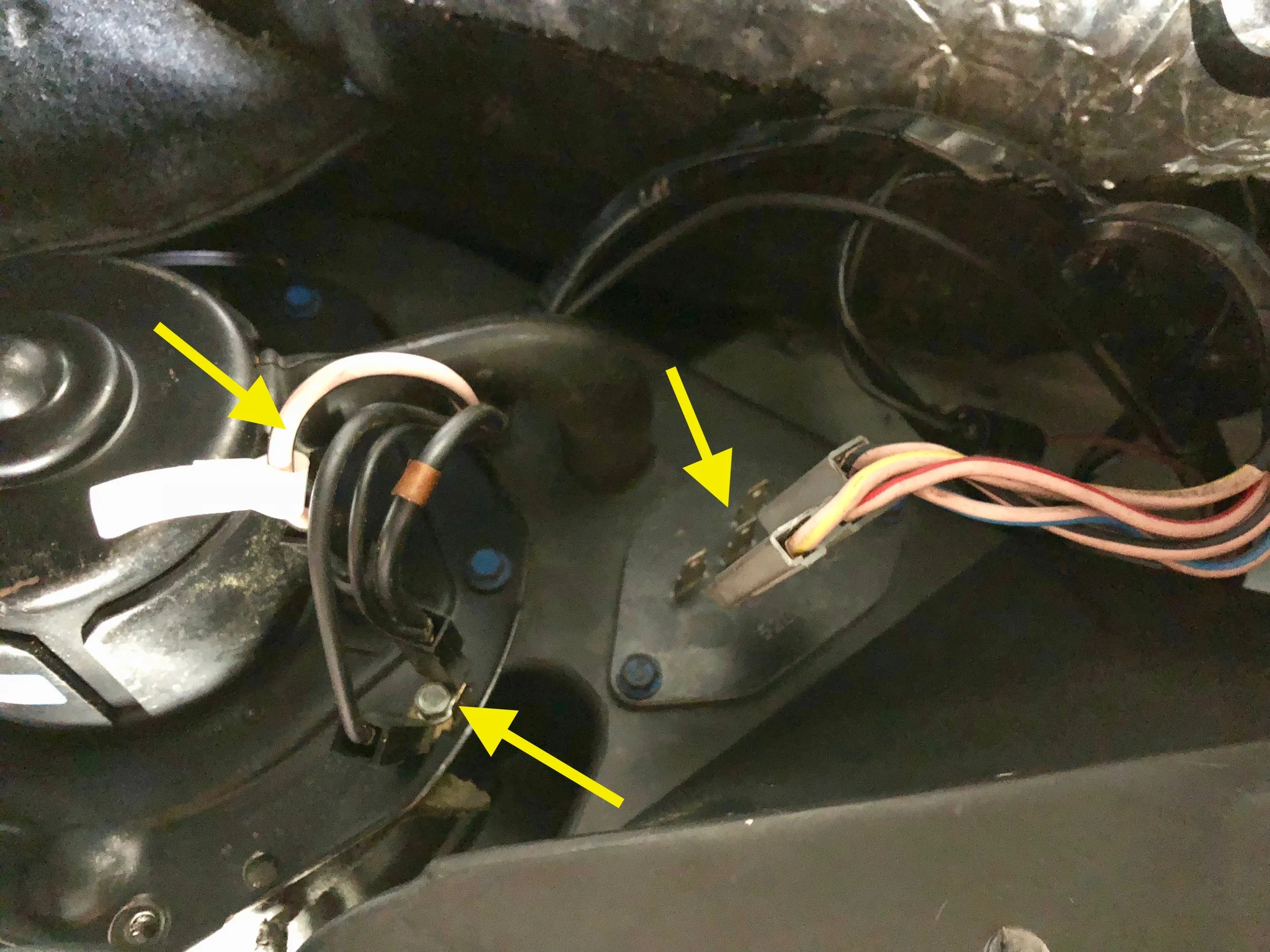 The power wire (left), ground wires (left bottom) and resistor connector (right) are highlighted here. The blue hex nuts around the perimeter of the motor (six total, left) need to come out, as well as the two on the resistor (right).
