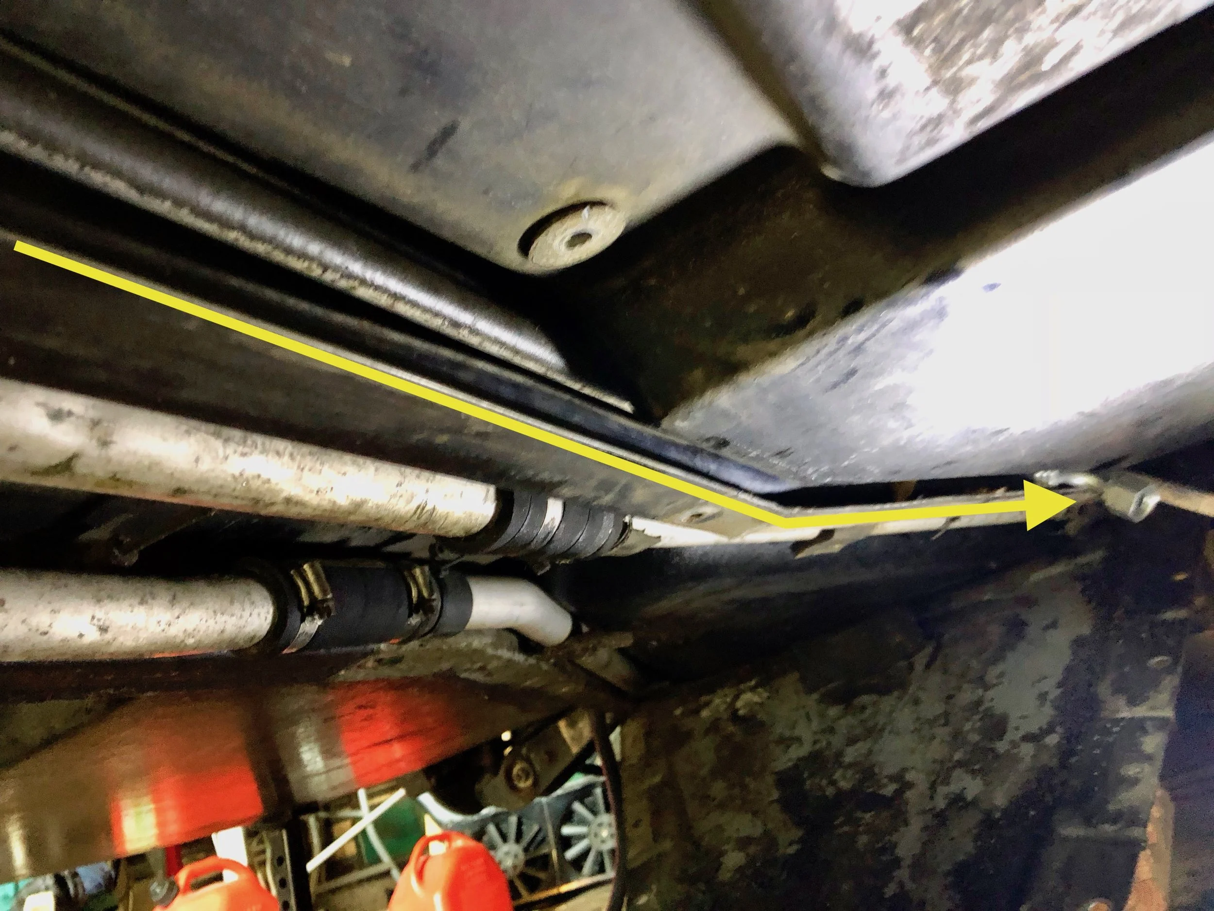 The yellow line shows the path of the hose, with the arrow head pointing at the connector. Jacking the body separates it from the frame just enough to fit it through.