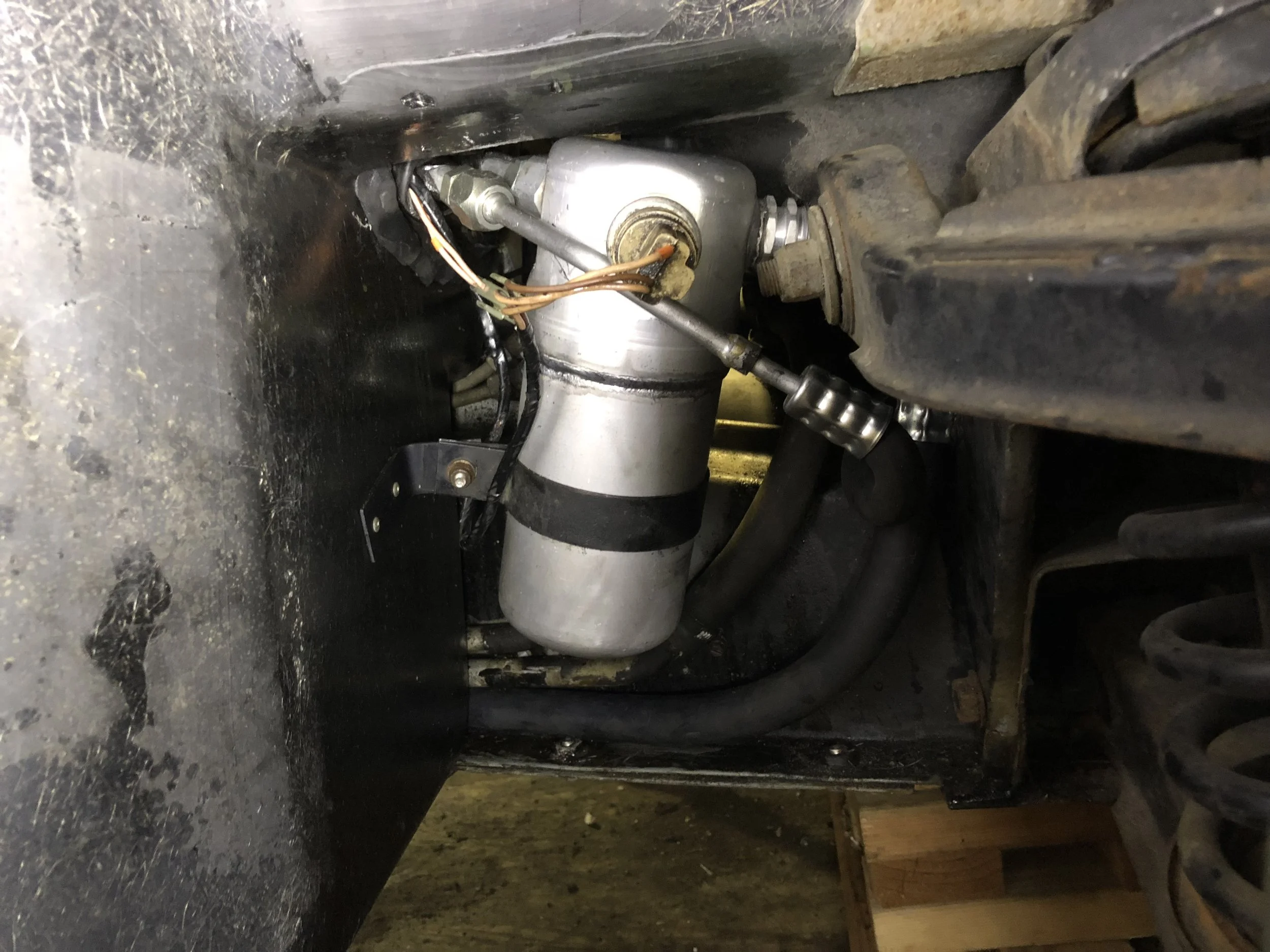 Final installation of the accumulator, the old low pressure switch, the new line from the condenser that wraps around the accumulator, and the new compressor line that runs under the accumulator and plugs into the side on the right.