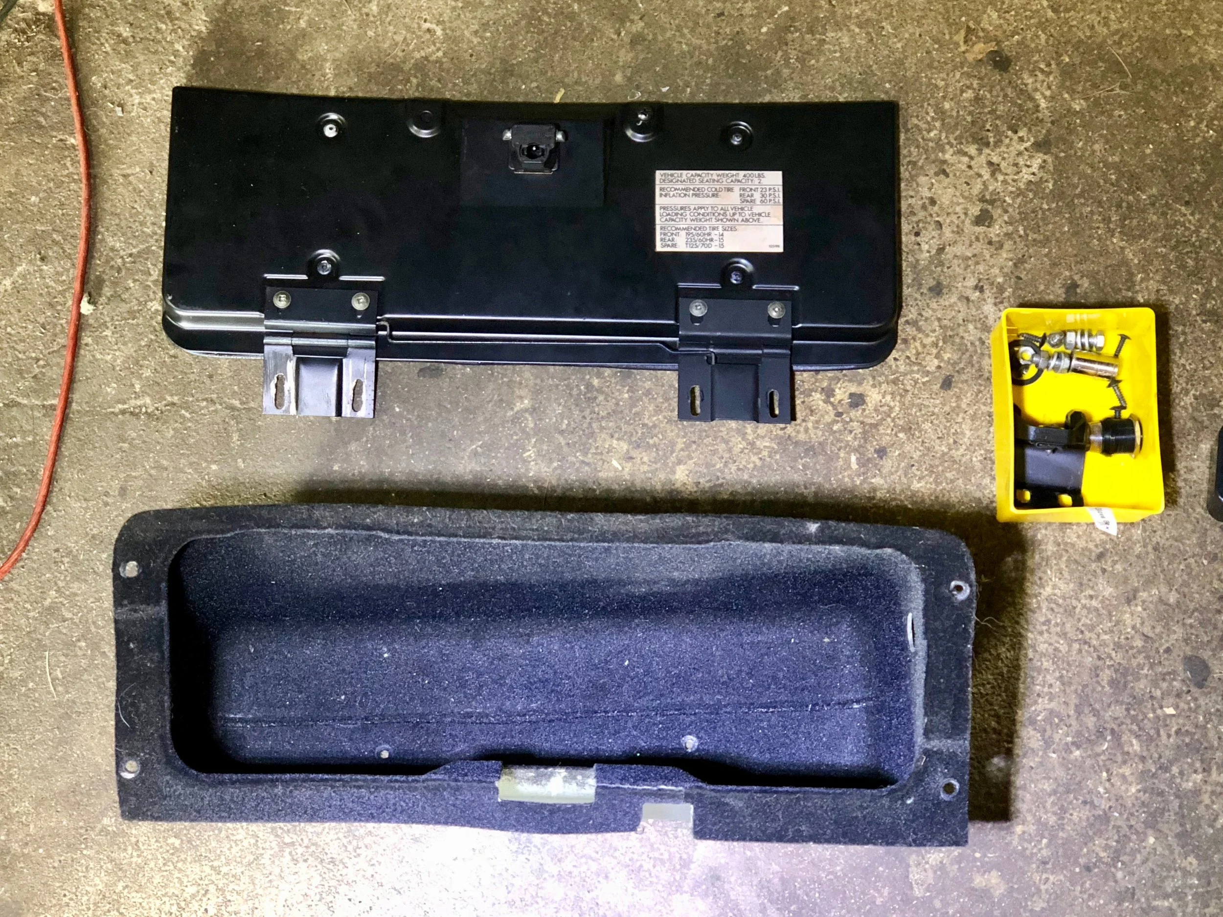 The glove box removed from he car. There are four screws around the edge, two screws on each hinge, two bolts for the latch, and the light through the side.