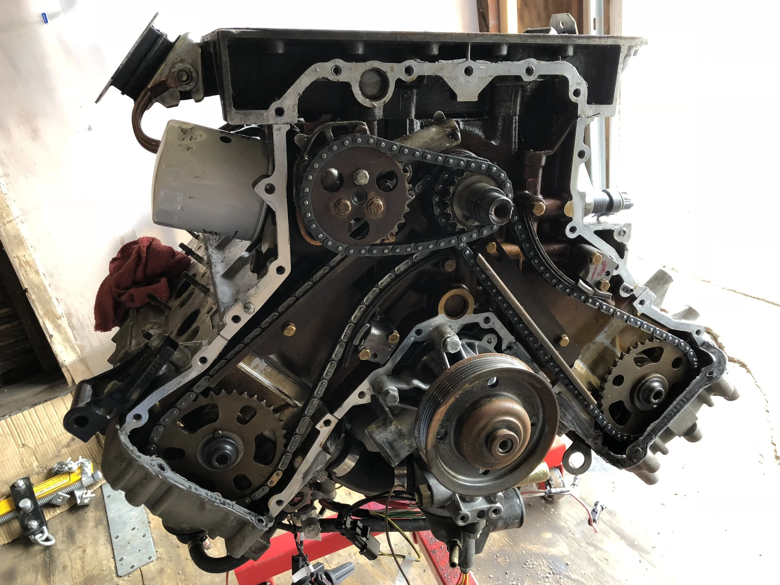 The upside down engine with the timing cover removed. The oil pump is still mounted behind its sprocket.