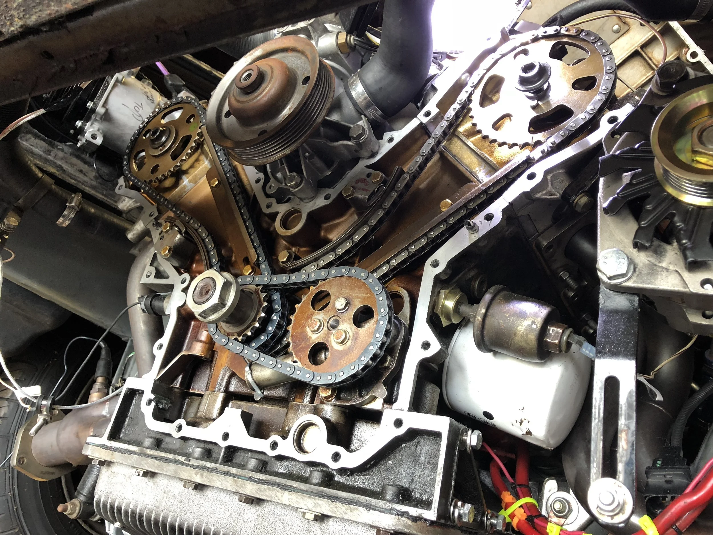 Engine mating surface cleaned with razor blades and scouring pads, ready for the cover to be re-installed after re-timing. The 2.8L-style oil pressure sender installation is also visible on the passenger side near the oil filter.