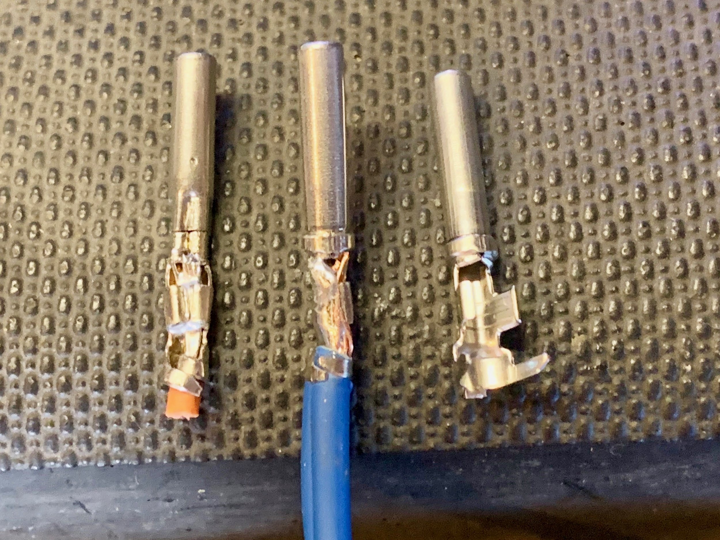 Incorrectly crimped connector on the left. Notice that the ring (which secures the pin inside the socket) at the base of the pin is crushed, while in the middle it is not. The rightmost pin hasn’t been crimped yet.
