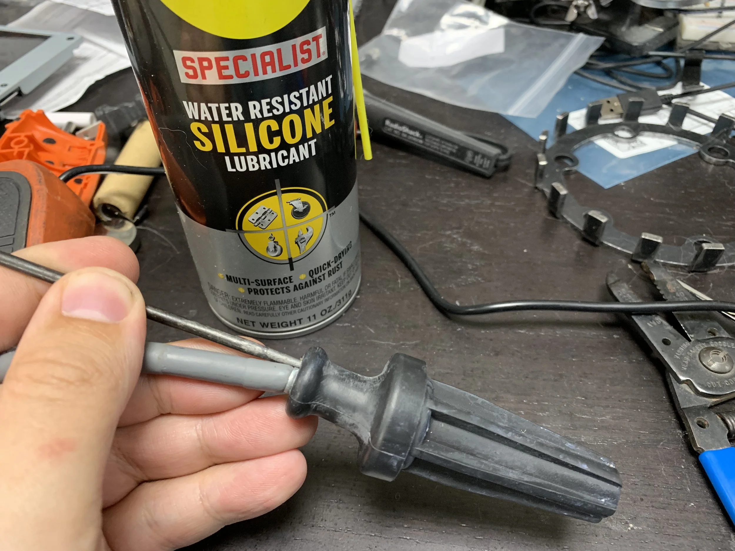 After spraying down the boot and wire with silicone lubricant, insert a pick on either side of the wire to loosen it from the boot, and then firmly pull the boot to slide it off the wire.
