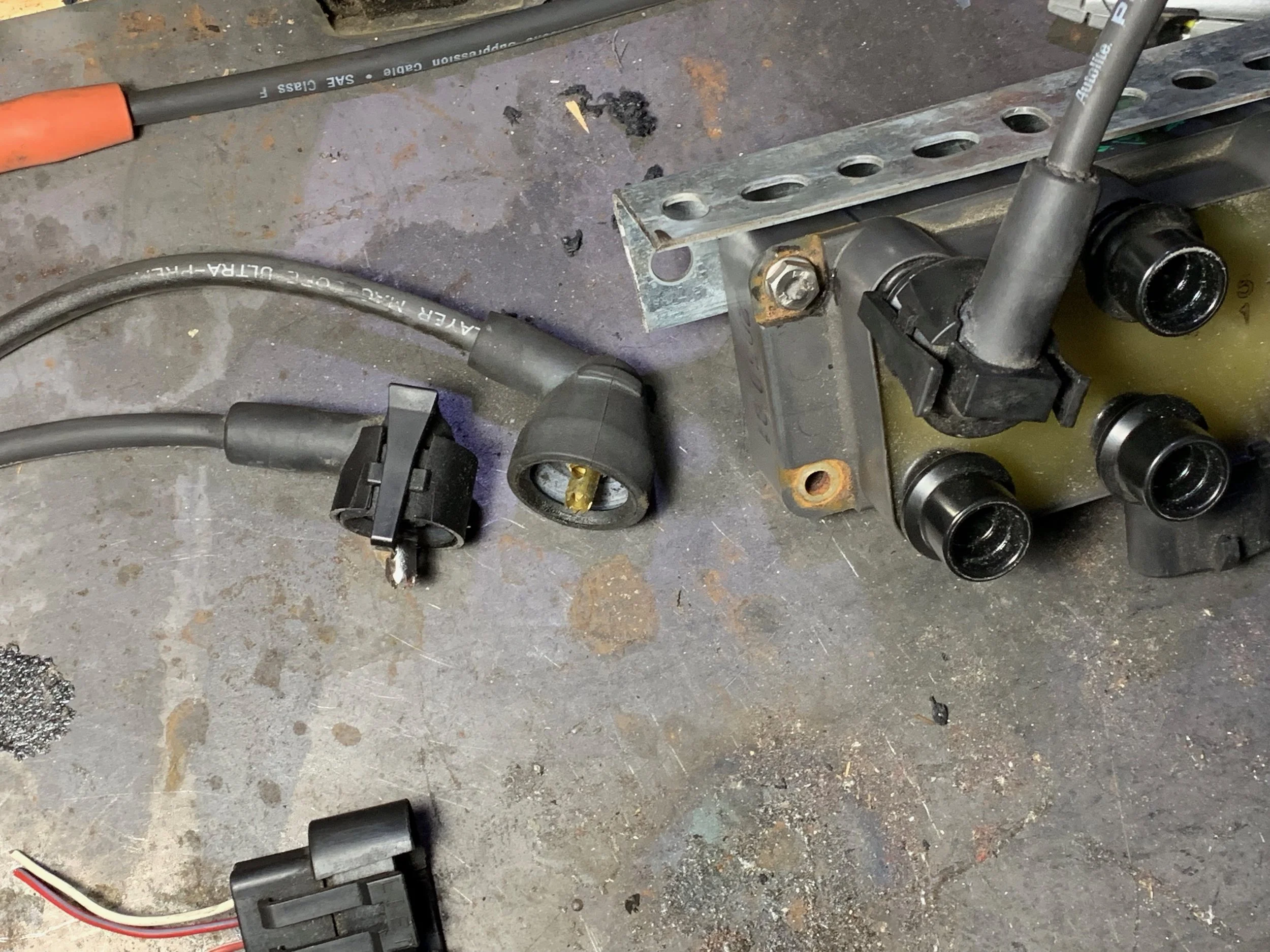 The EDIS 6 coil pack (right, cropped) with one clamp-on spark plug wire connected. Two steps of compatible wire ends are also shown (left). The connector pigtail is partially visible as well (bottom).
