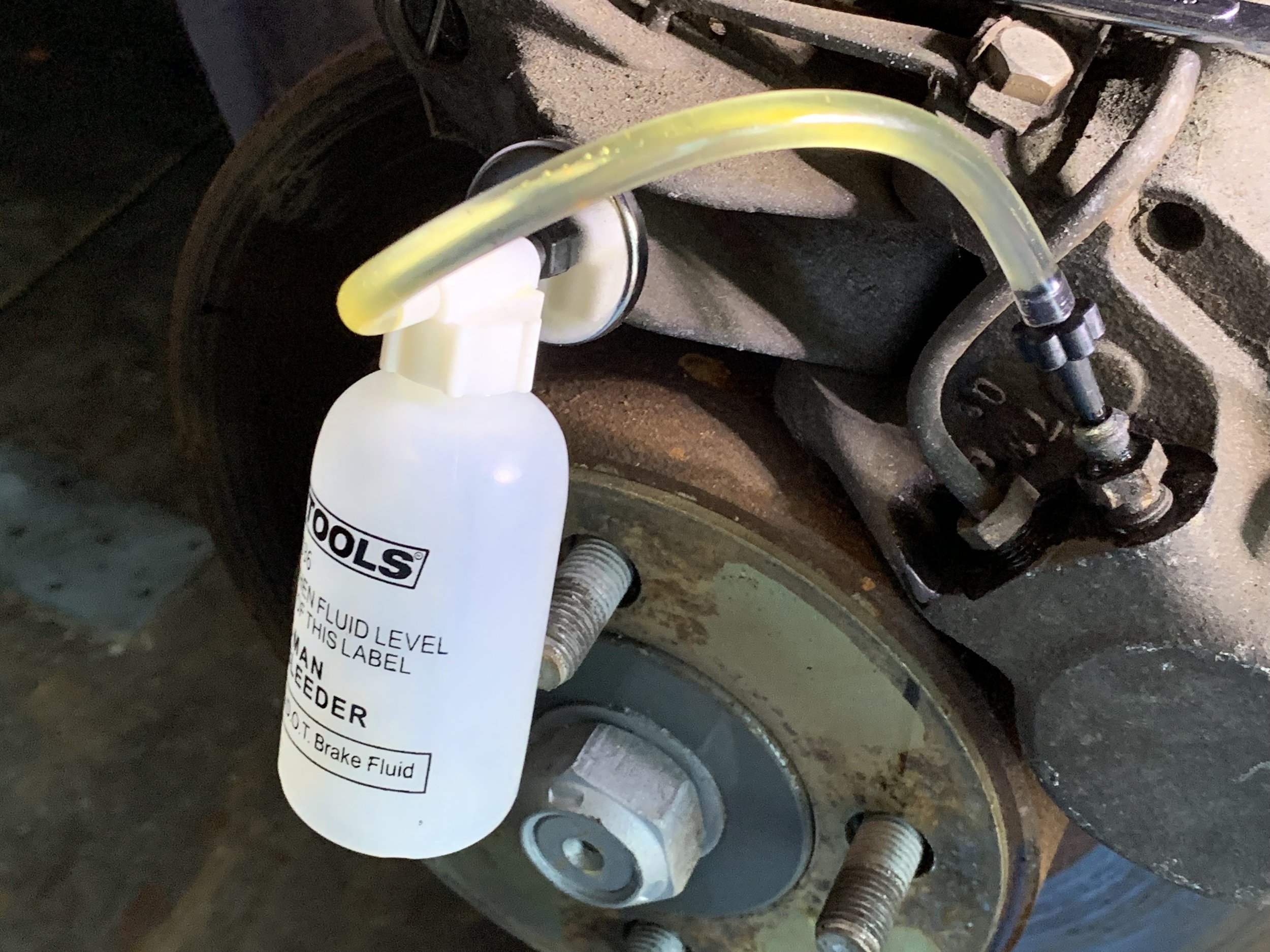 Old, yellowed brake fluid being drained from the caliper.