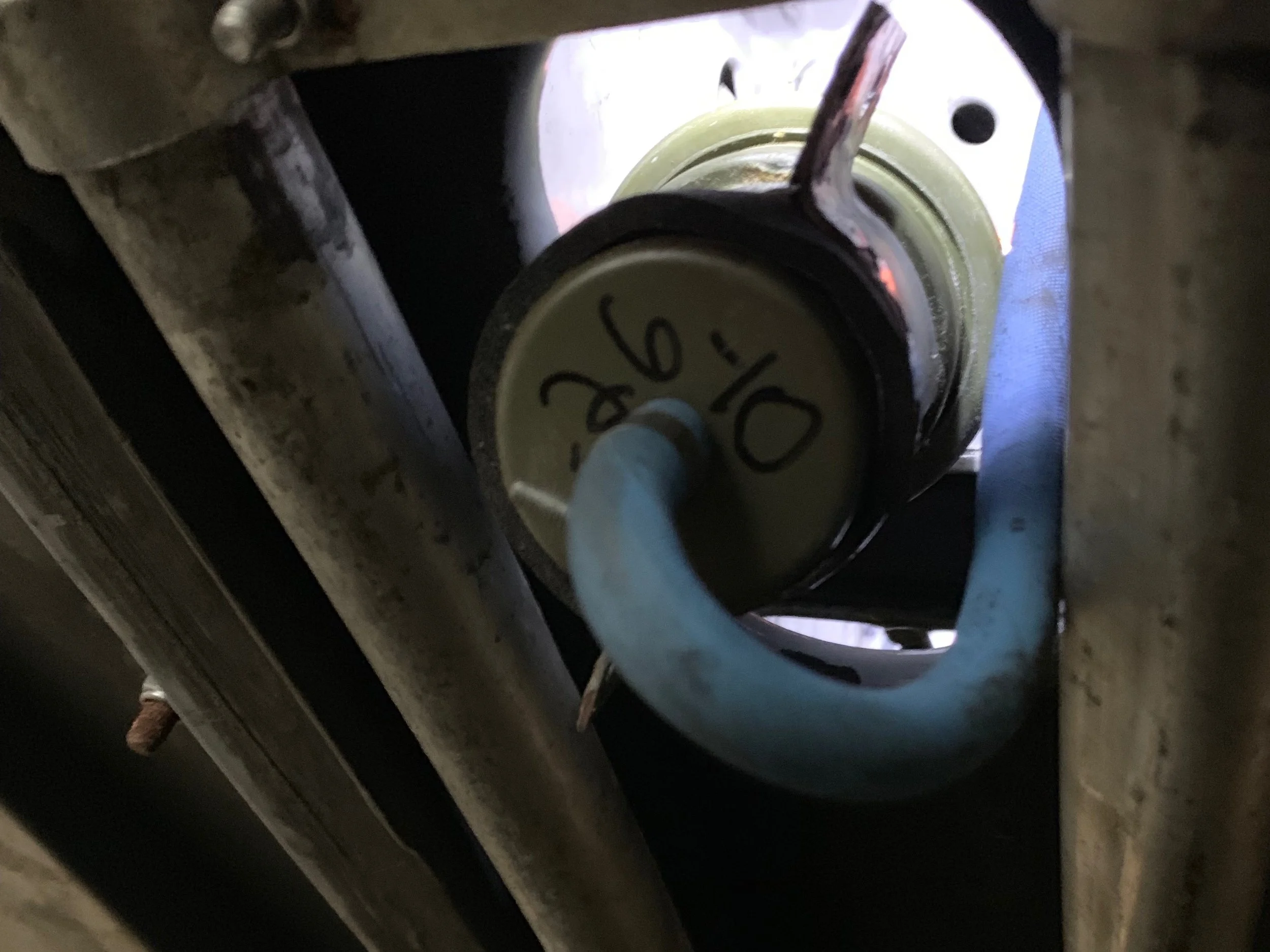 The accumulator unmounted from the bracket, but still connected by the blue hose on one end and the orange hose on the other.