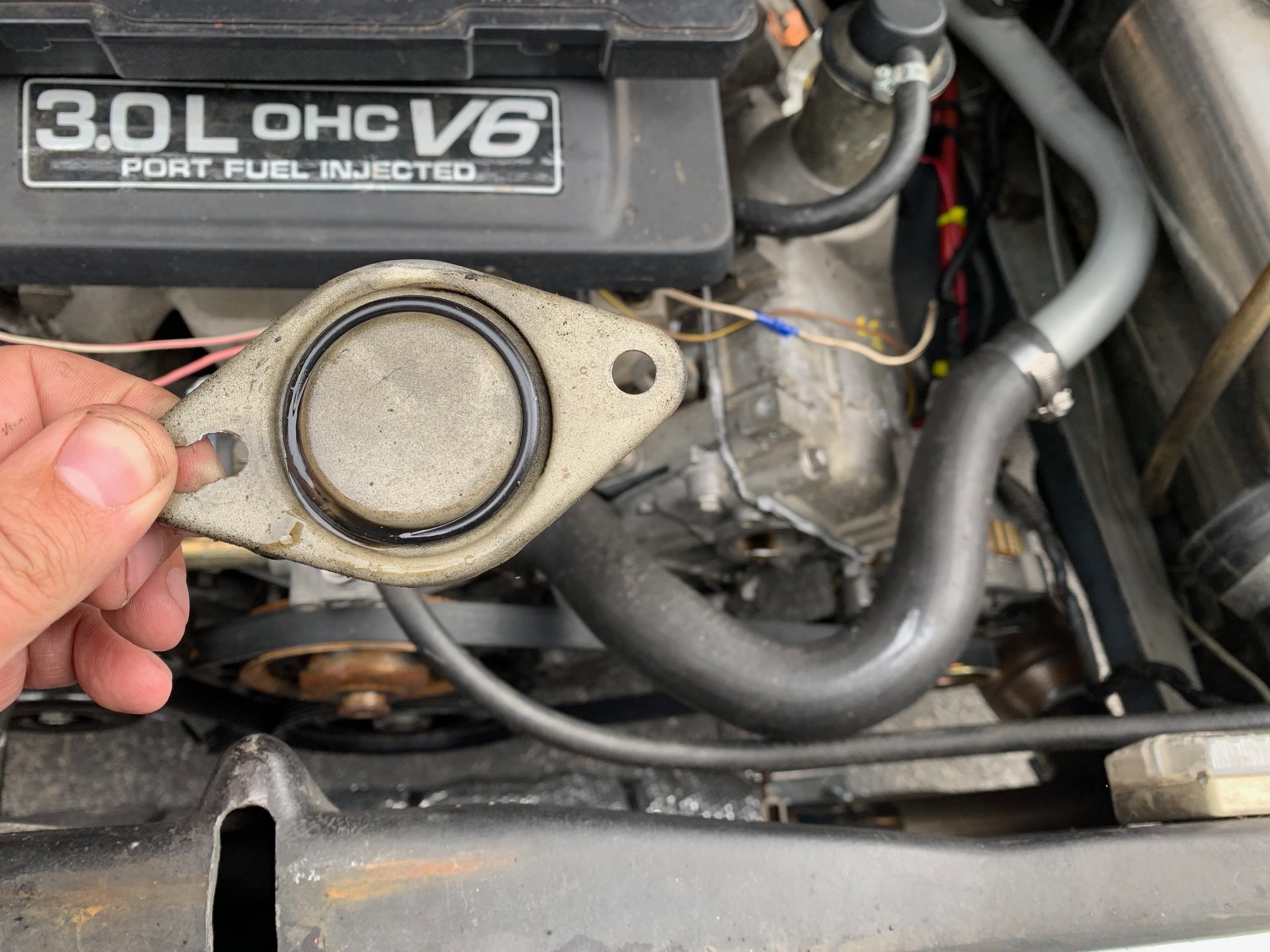 The cap was sealed with a simple O-ring, which worked on the 2.8L but not on the 3.0L. The elongated hole on one side is to deal with the different hole placement on the 3.0L engine.