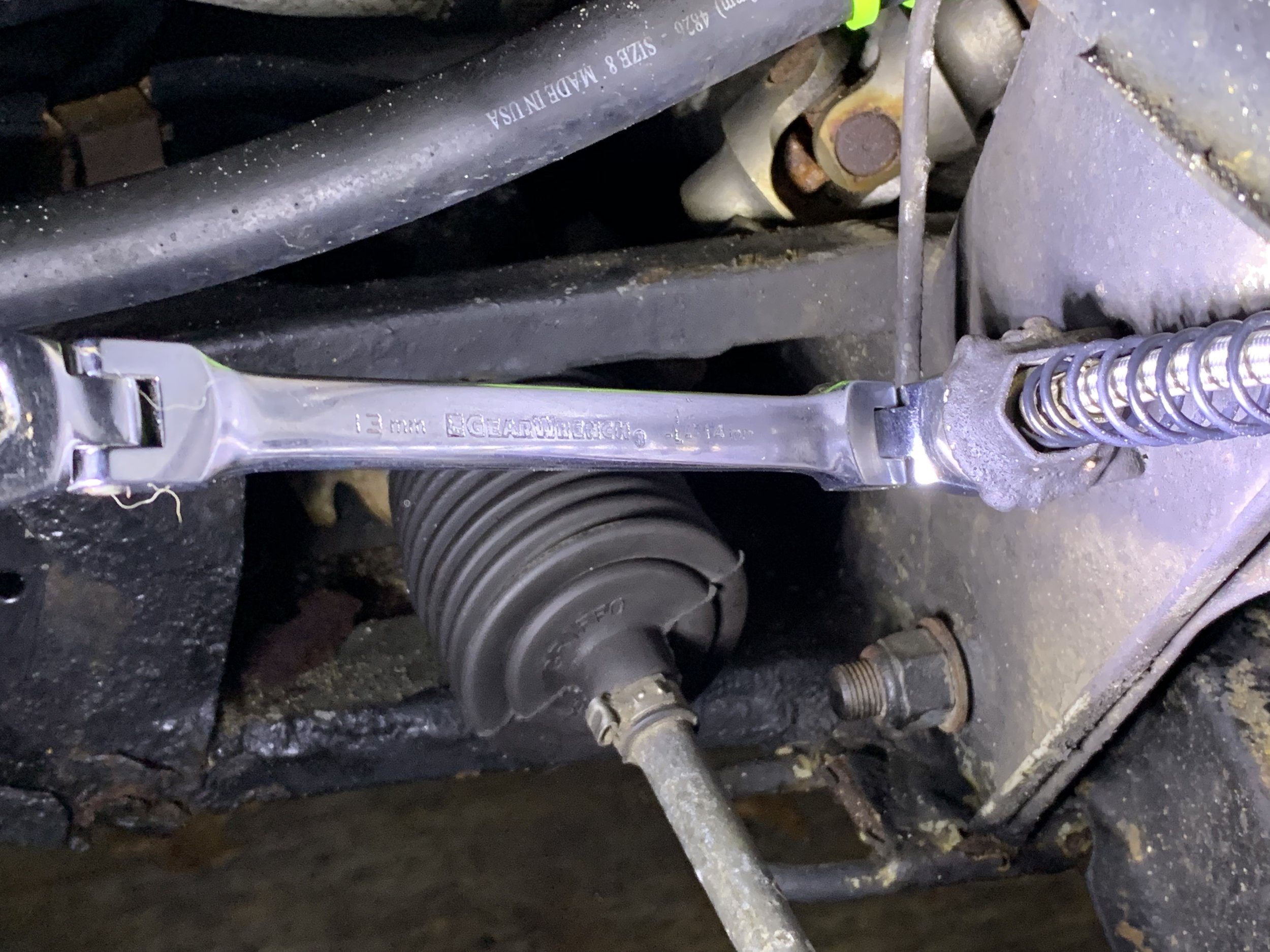 Using a 13mm wrench to remove the other end of the flex line from the hard line to the brake reservoir.