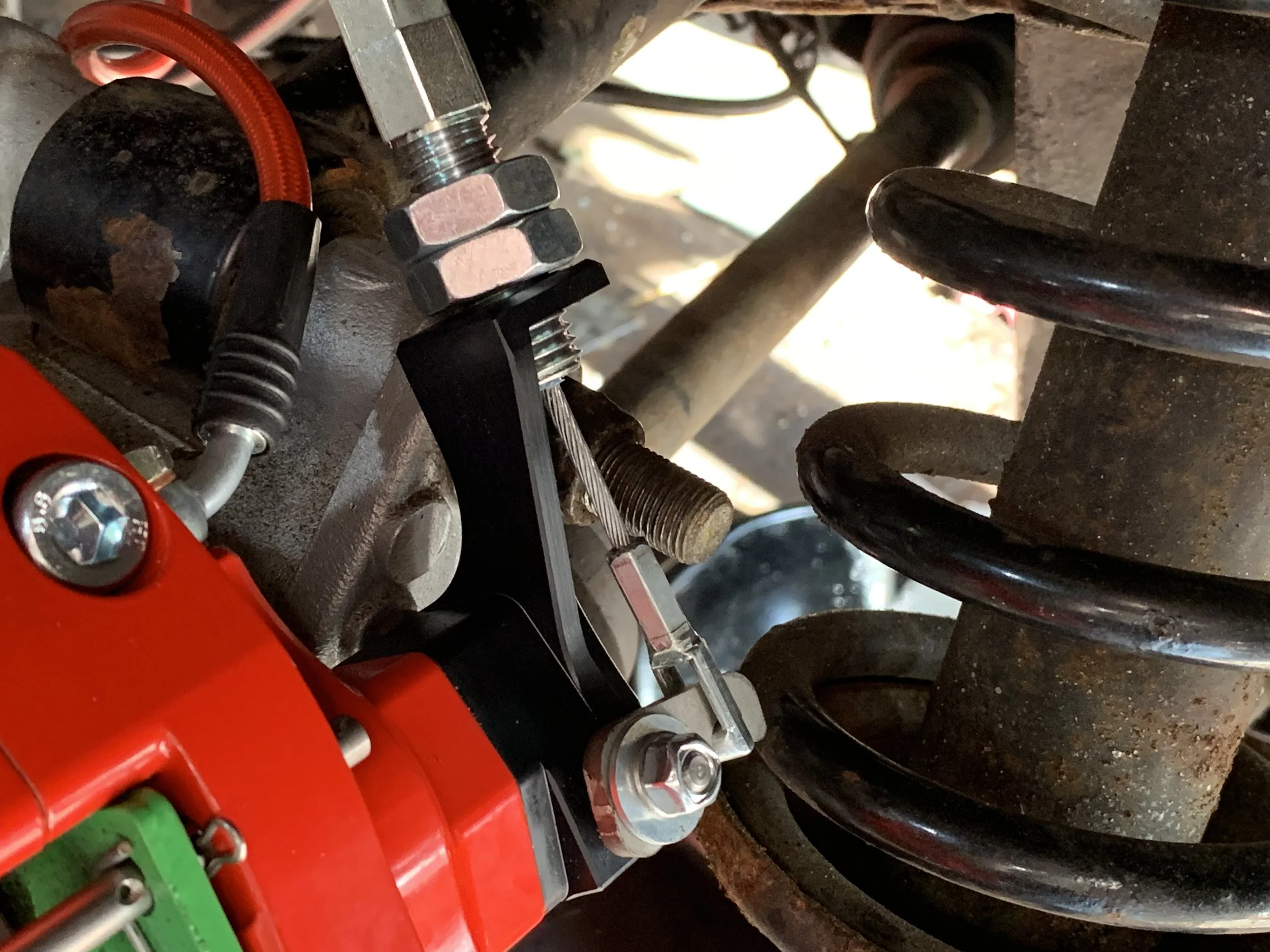 The cable hooked onto the hand brake lever on the caliper, with the two nuts sitting outside of the bracket. The nuts should be adjusted so that there is no tension on the lever when the brake is not in use.