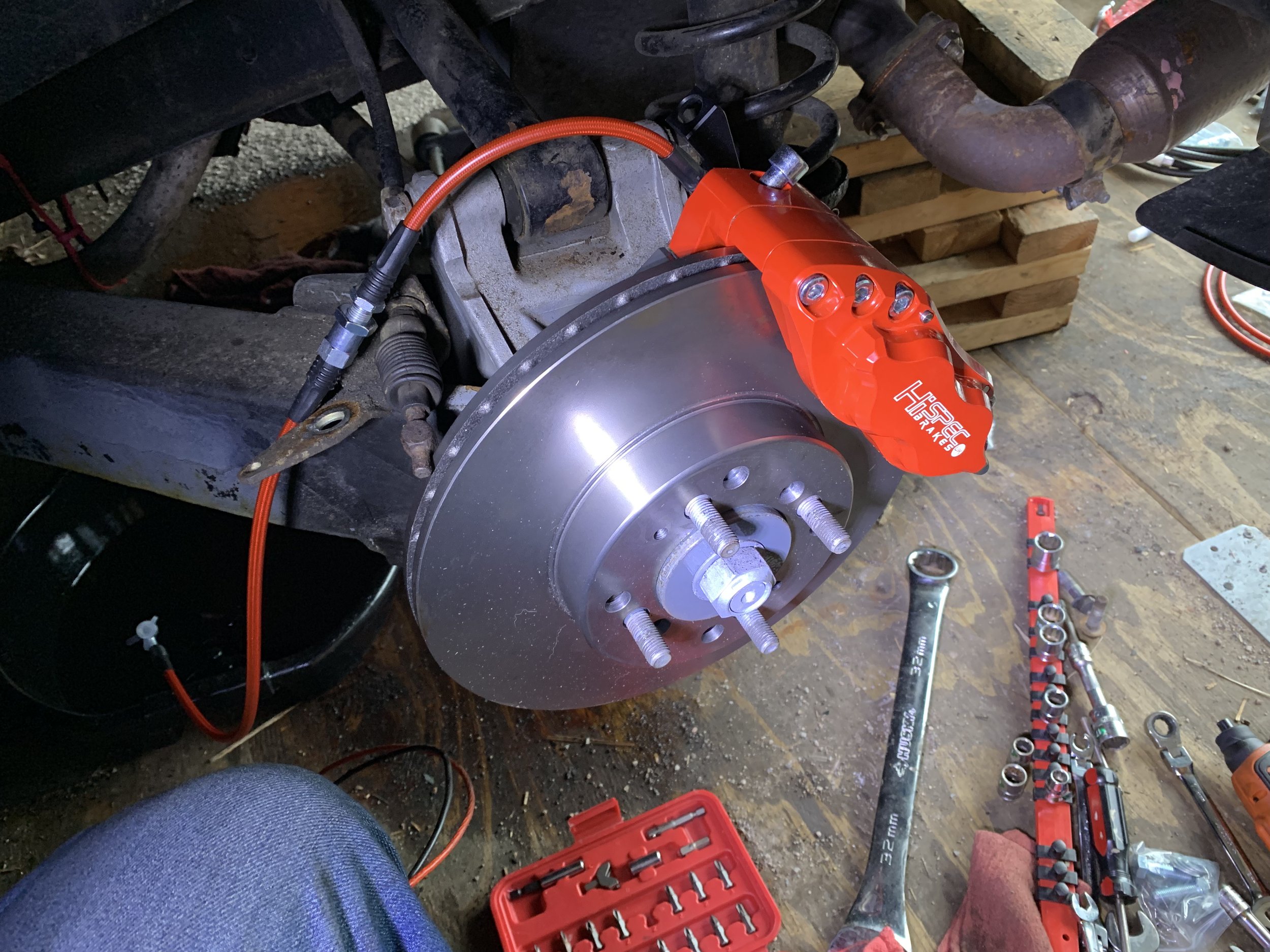 The caliper being test fit. Note that the brake lines are installed incorrectly here — the short line is attached to the hard line, and the long line is attached to the caliper.