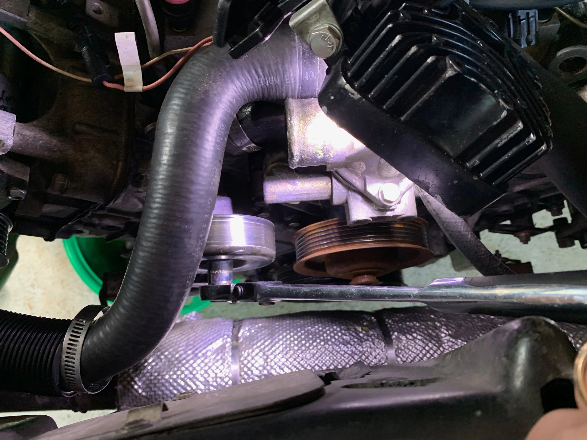 Removing the upper idler pulley to access one of the water pump bolts.
