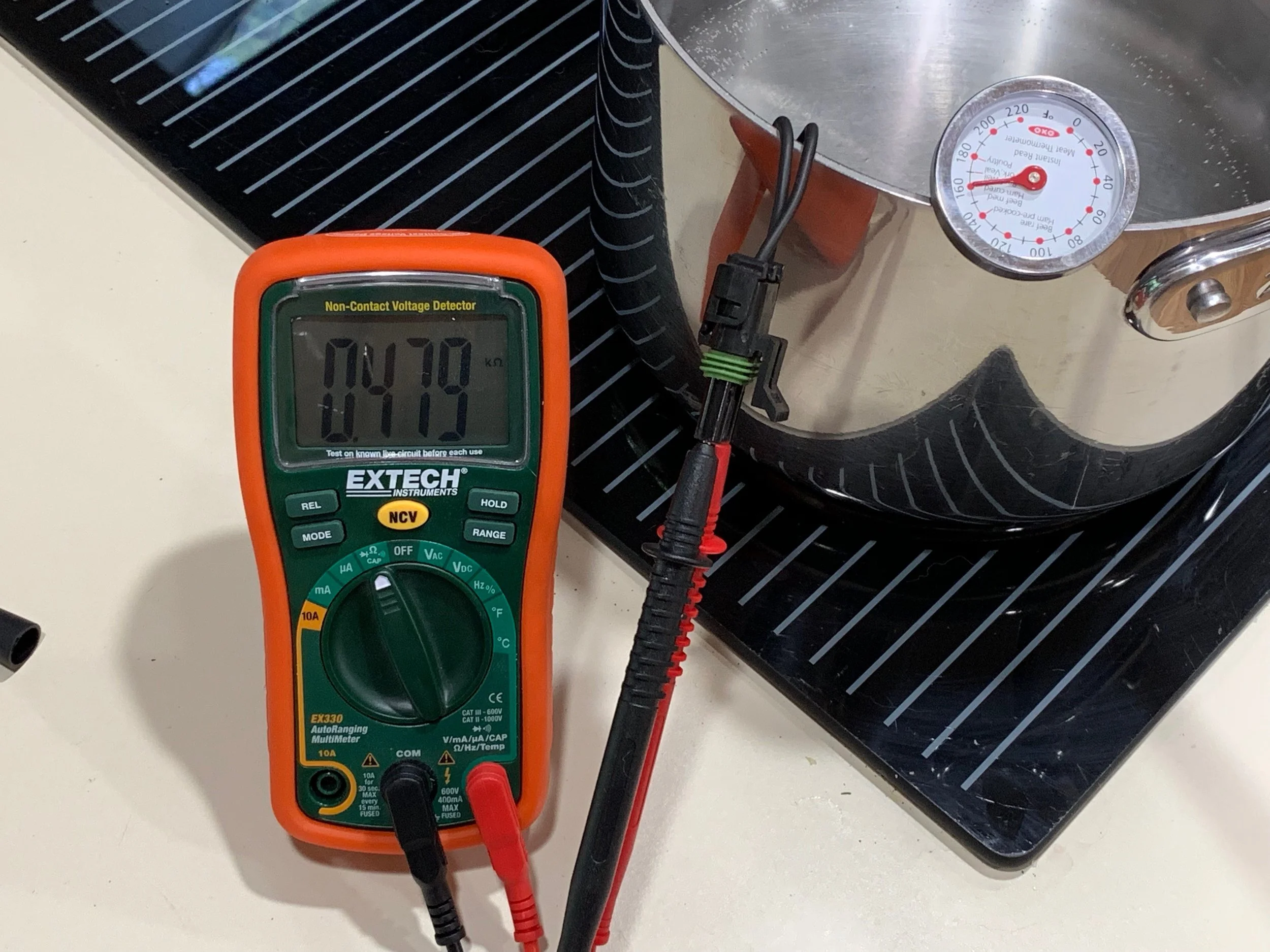 Using a thermometer, an ohm meter and a pot of boiling water to calibrate the high end of the coolant temperature sender. In this picture the sender is still warming up. Only the end of the sender is in the water, not the whole thing. Also, the meat thermometer would read differently depending on how much of it was in the water, so I’m not sure how well I did my calibration here. The ice water and room temperature readings were much easier (I forgot to take pictures of those).