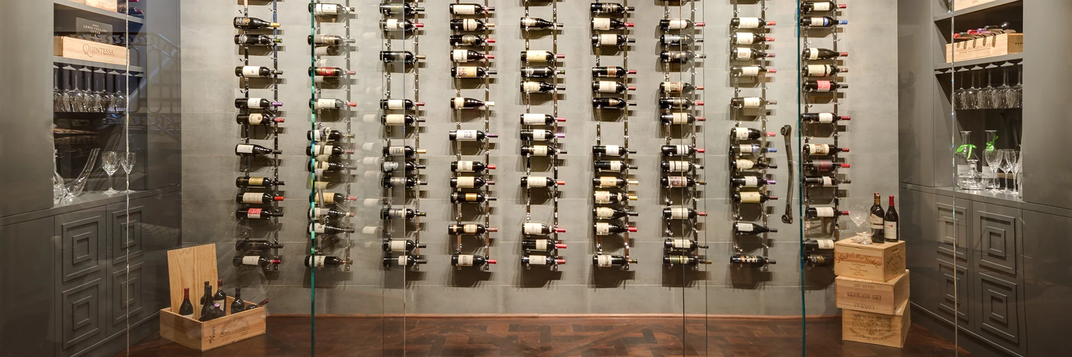 Wine Room ( Gallery). This room was designed to have the wine become an art object in the home. This room was also a shell of a space. The espresso room was originally conceived to be the wine room. The homeowner did not want that large of a space dedicated to wine and was more interested in coffee and the concept of having an espresso room. He loved the idea of having wine stored in an unexpected place and an unexpected way. We carved an area out that had no defined purpose and decided to create a wine wall. There was a soffit that existed in the space and i extended that soffit out further into the room in order to create the illusion of having the wine area dug out of the room. To add to that illusion, i painted the entire area dark with the tile and cabinetry to closely match. The tile utilized on the back wall is a porcelain metallic to give some depth to the space. The racks were custom made in chrome to add a flash. Starfire glass encloses the space. 