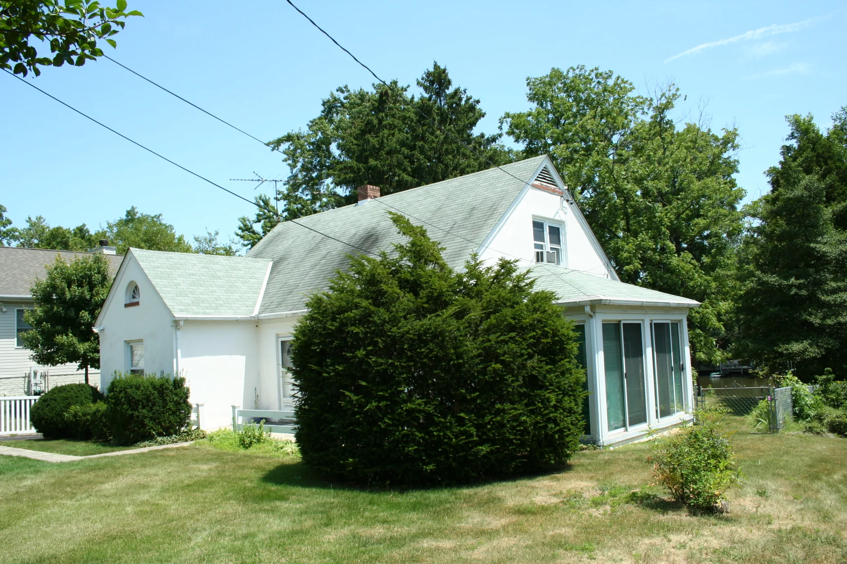 Before: the right wing with the nearly flat roof will be removed and reconstructed to serve as the Music Room; the rest of the first floor walls will remain mostly intact, but a second story and walk-up attic will be added, along with a front garage, foyer, and covered porch addition; a rear family room addition; and a rear breakfast room bumpout. 