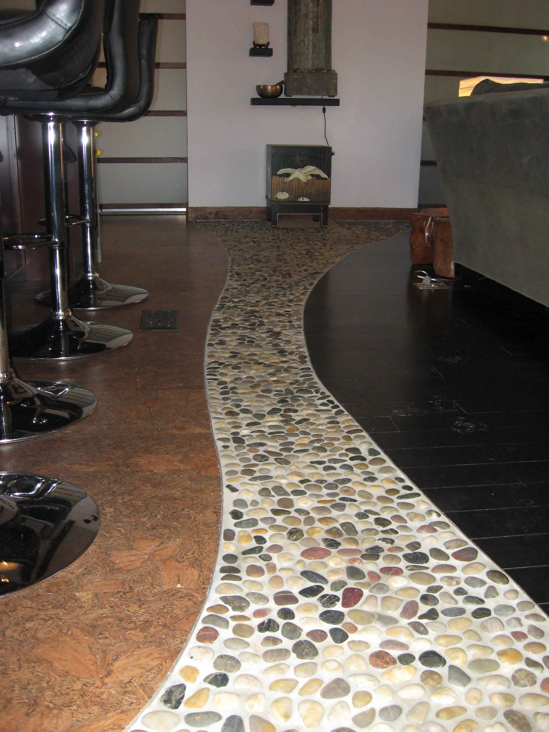   Pebble river runs through this great room, separating the reconfigured kitchen from the living and dining areas, with its source the wall-hung fountain and its mouth at the door to the garden.   
