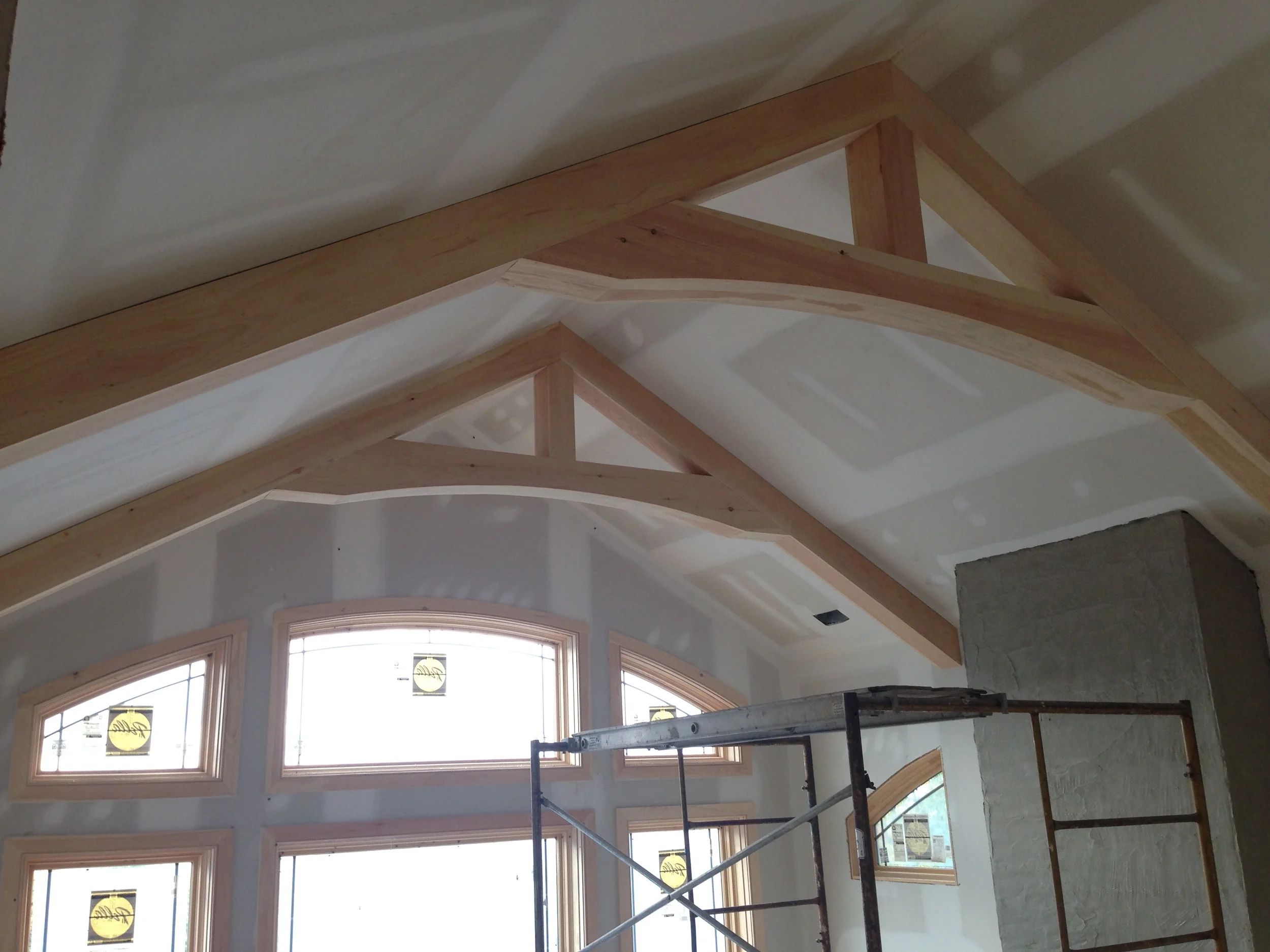  Faux timber trusses installed against the sloped ceiling, and centered on the fireplace. 