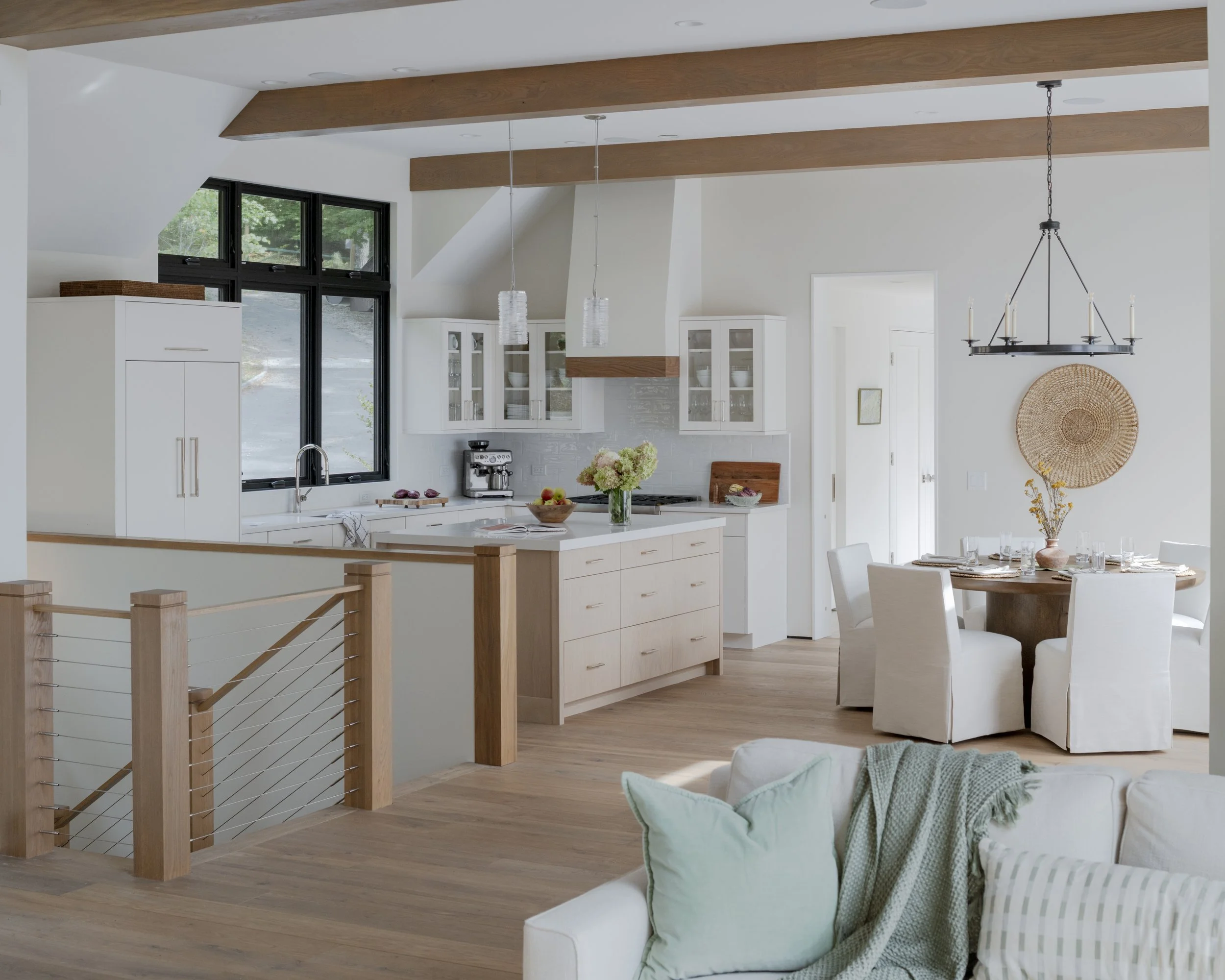 Open-concept kitchen and dining area with white cabinetry, a central island, a round dining table with white chairs, and natural wood accents.