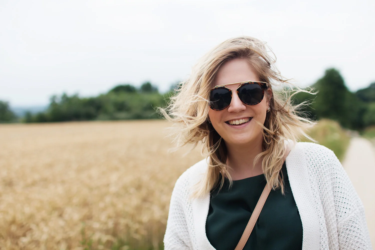 Smiling woman wearing sunglasses in front of wheat field