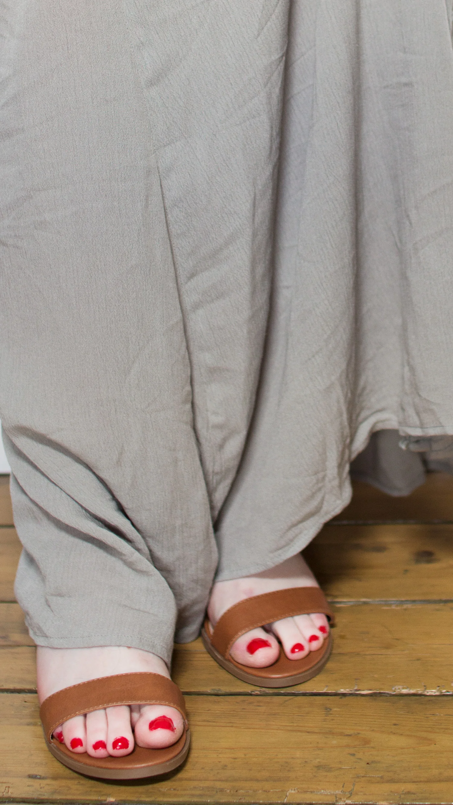 Feet with red toenails in brown sandals