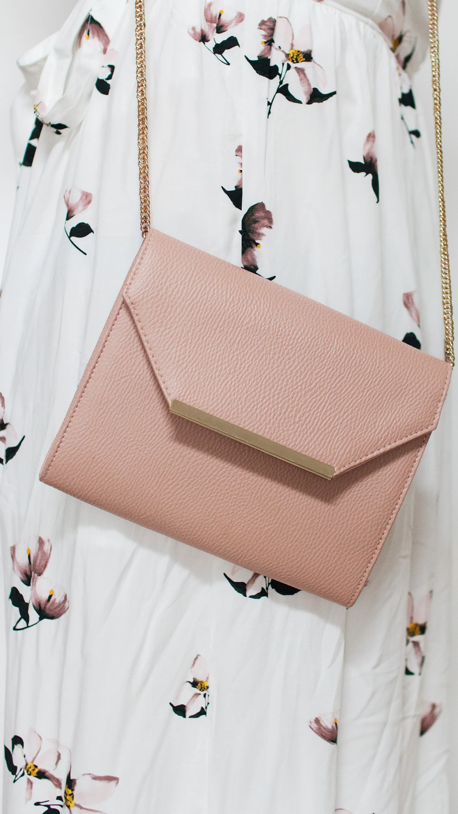 Blush coloured clutch bag against white floral dress