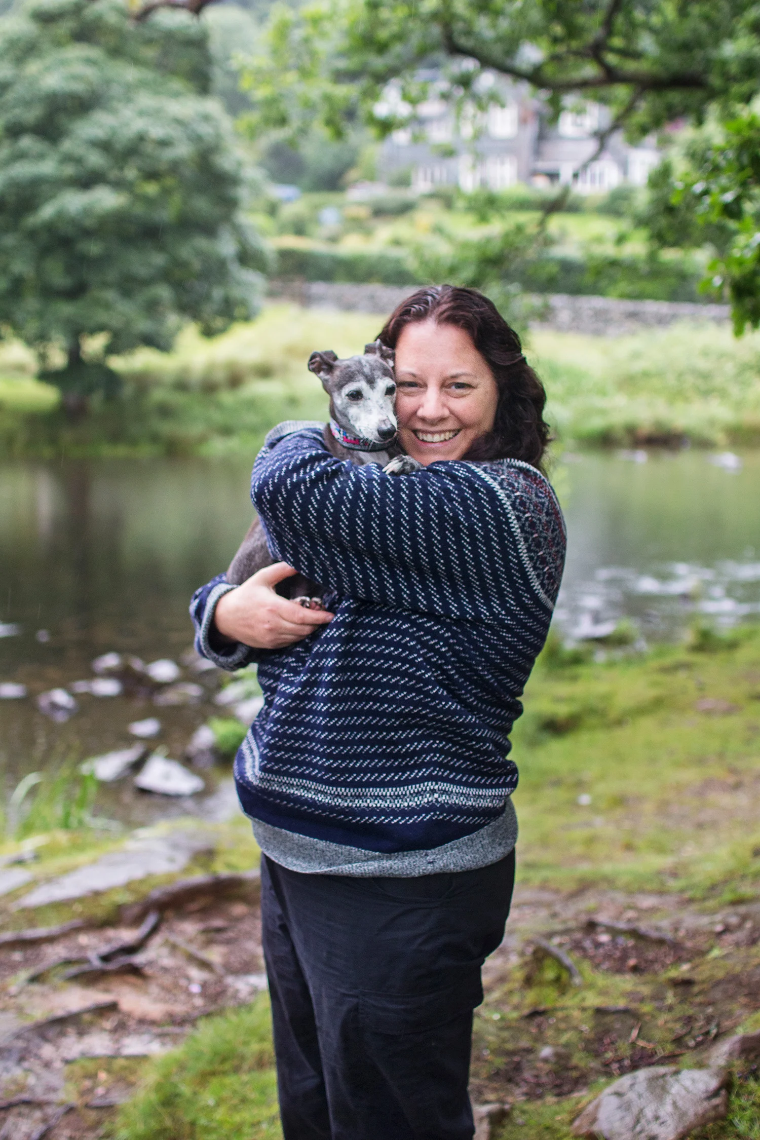 Woman smiling and holding her dog in the countryside
