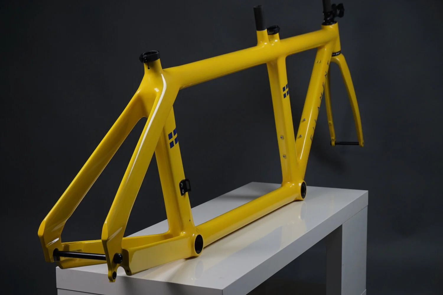 Rear view image of a Filament triathlon tandem bicycle frame with a custom paint job of yellow with flag motifs.