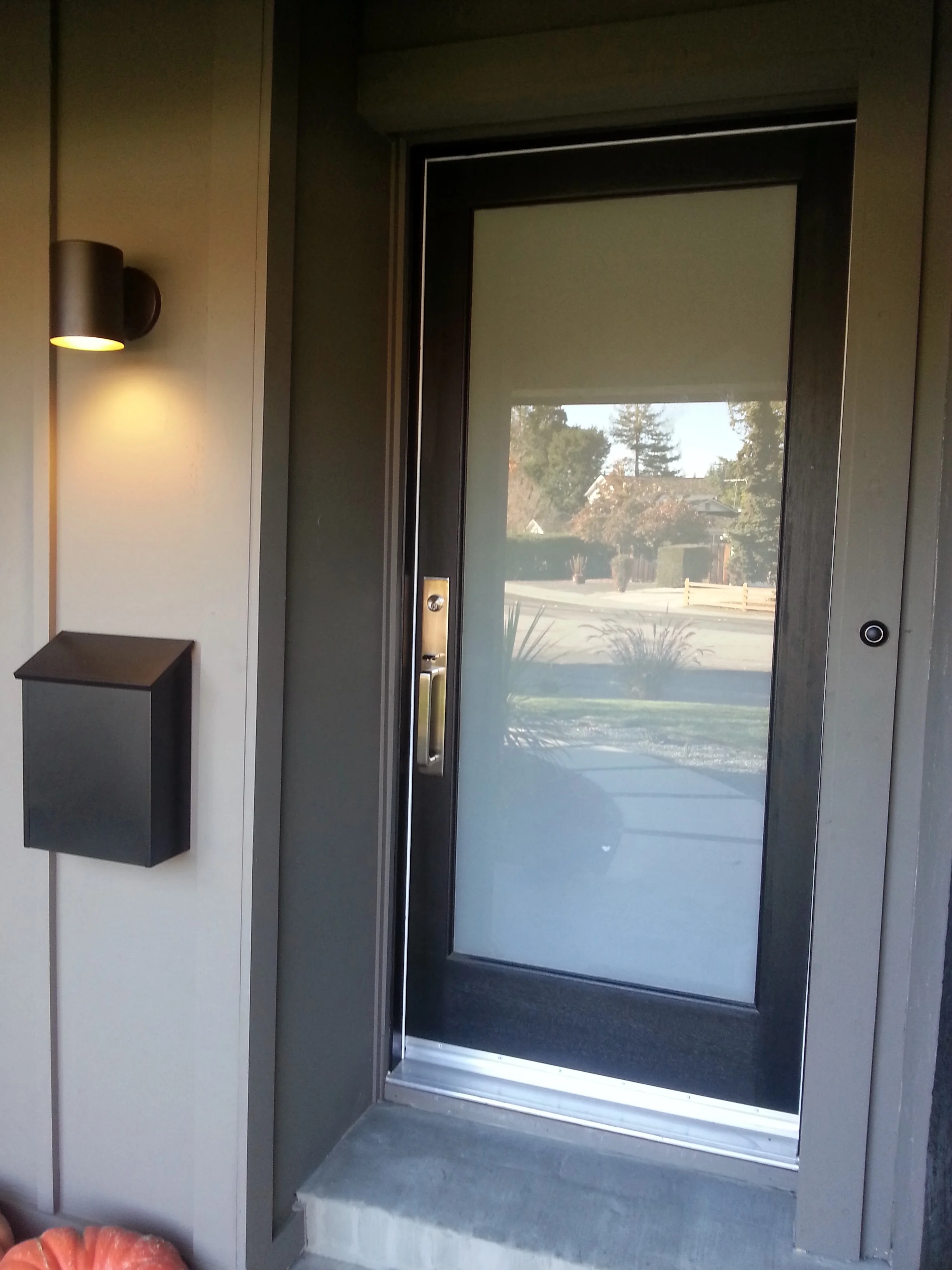 New laminated glass panel front door with lovely hardware, new lighting, mailbox and board and baton siding to cover the old brick, which also allowed us to run electrical for a hardwired doorbell. 