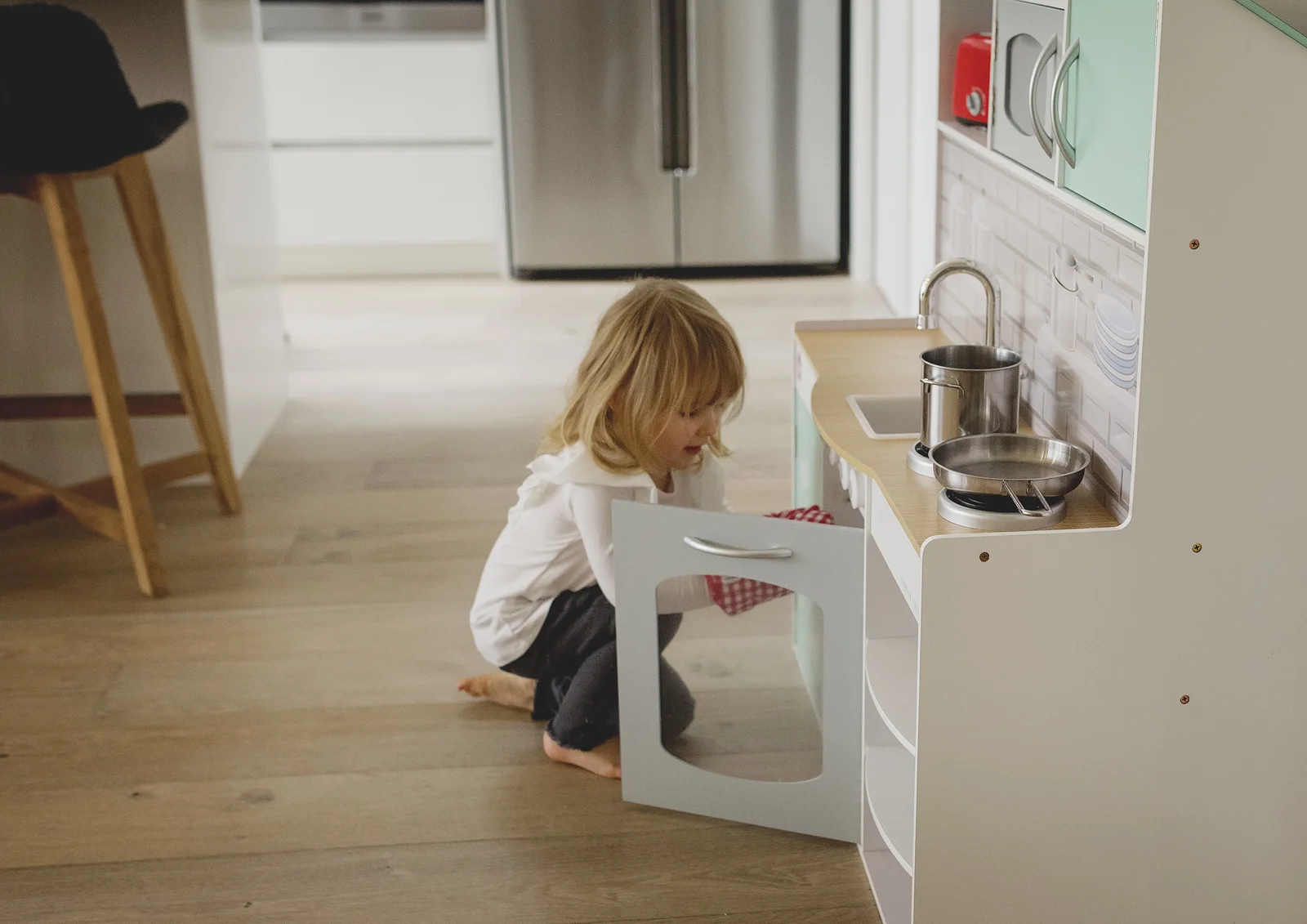 Little girl playing with her toy kitchen