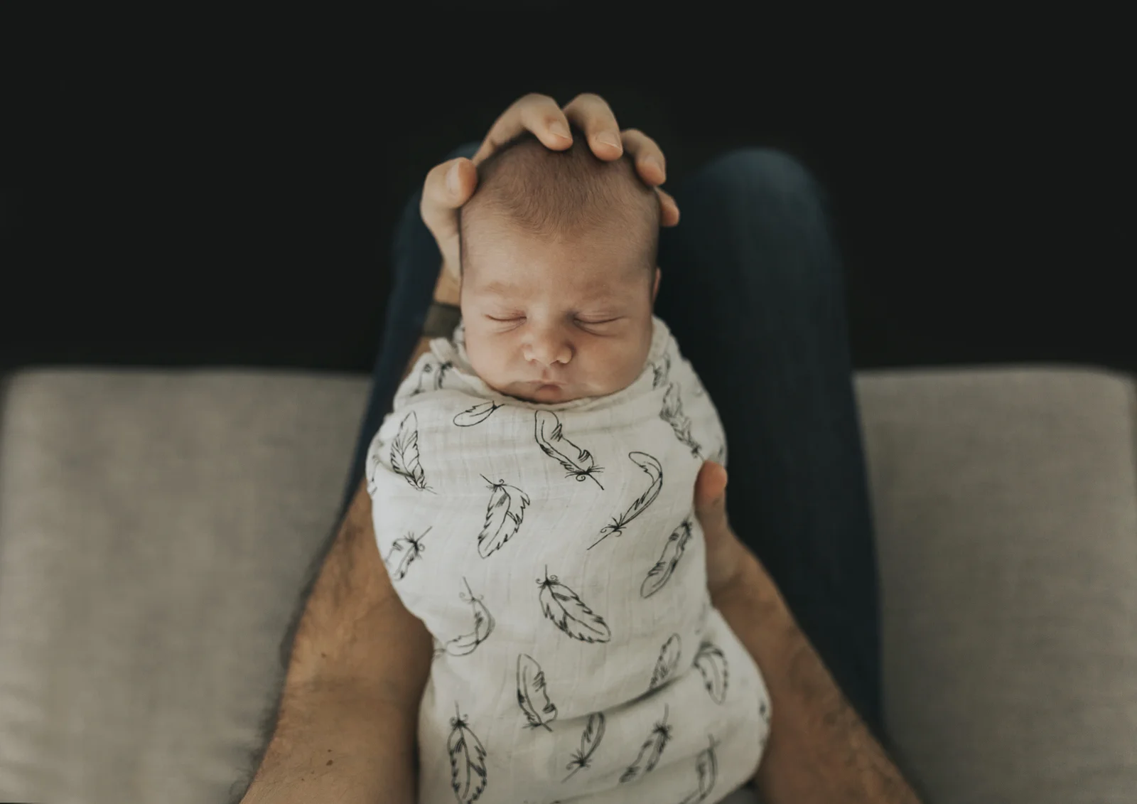 Newborn baby boy cuddled on his Dad's lap