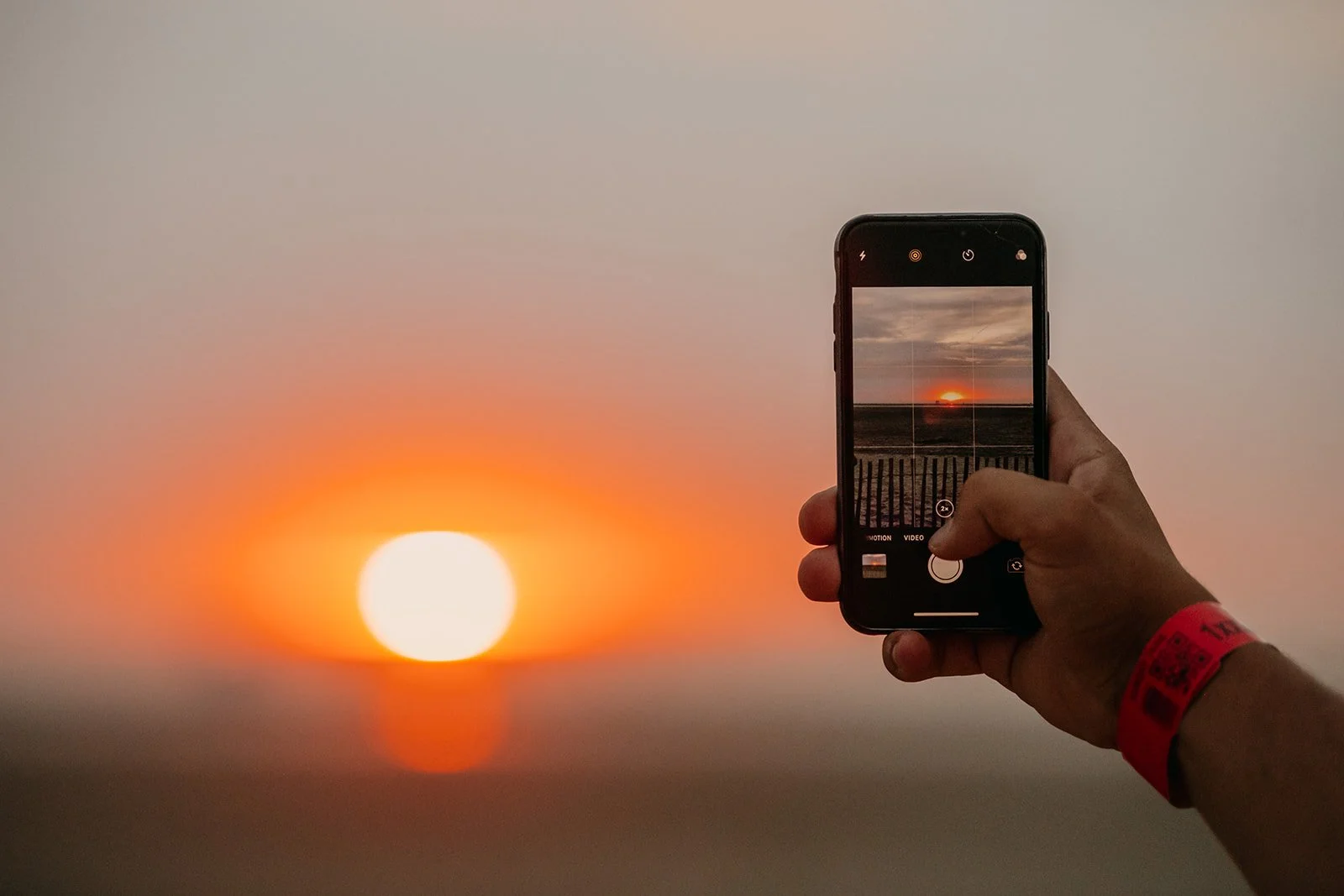 persoon die foto neemt van zonsondergang aan het strand