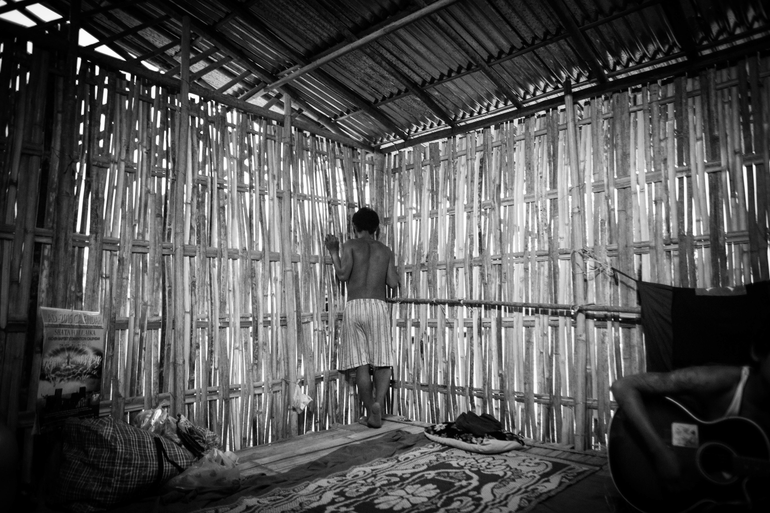 Confined to a bamboo hut, the new students at the YCC rehab center talk to the older students through spaces in bamboo slats of the "prayer room."