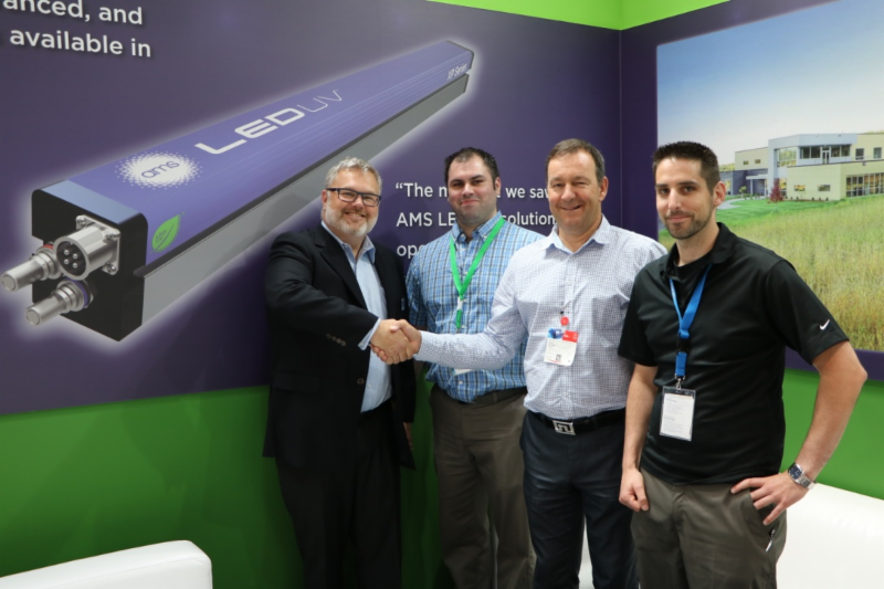 Hans Ulland of AMS congratulates Donald Caron of IML Labels upon the signing of the contract for their first AMS LED UV system for In-Mould Label production at drupa 2016