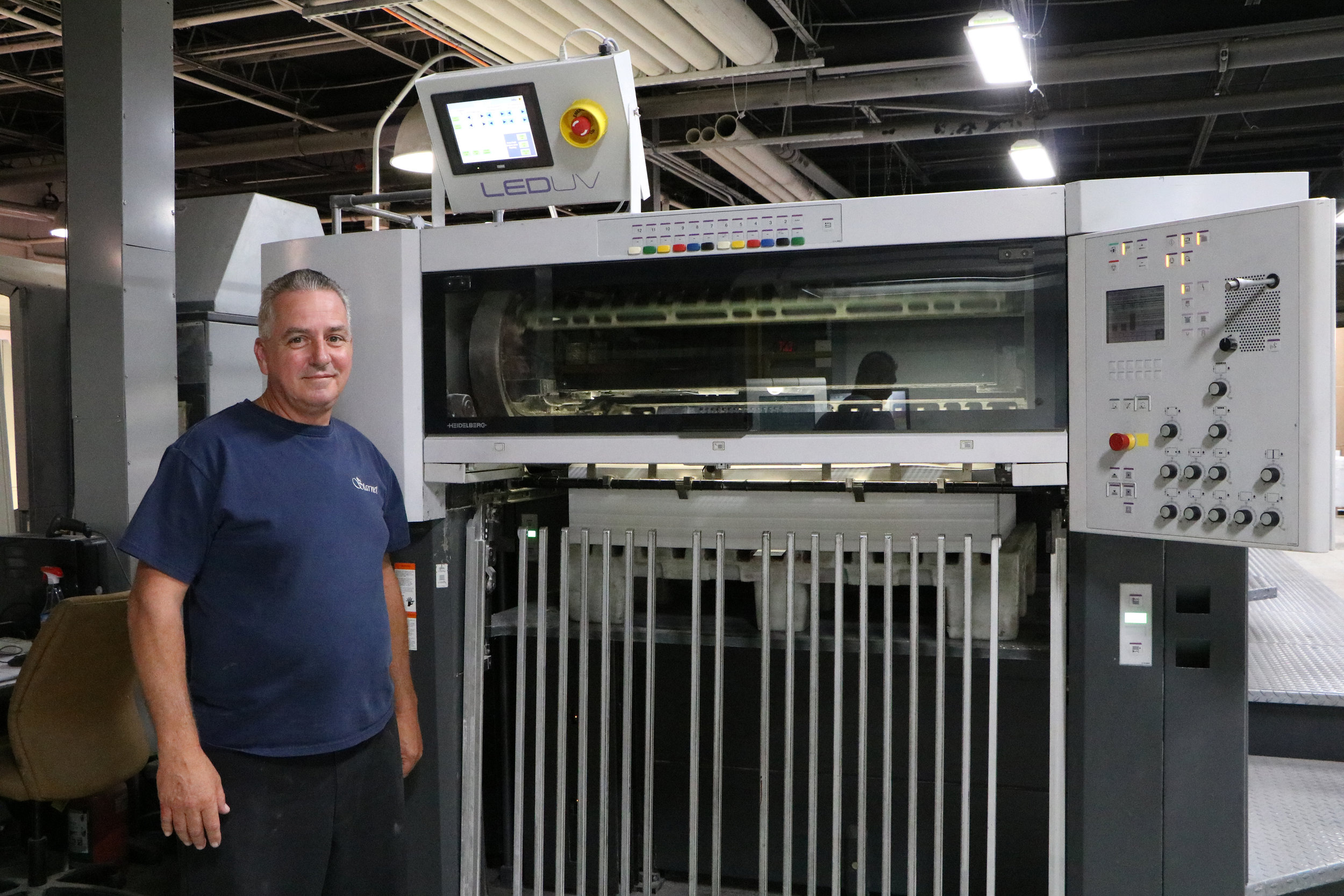 Veteran press operator John Cullen of Starnet Business Solutions pauses for a photo at the end of the company's Heidelberg Speedmaster press, which was retrofitted with an LED UV curing system from Air Motion Systems. 