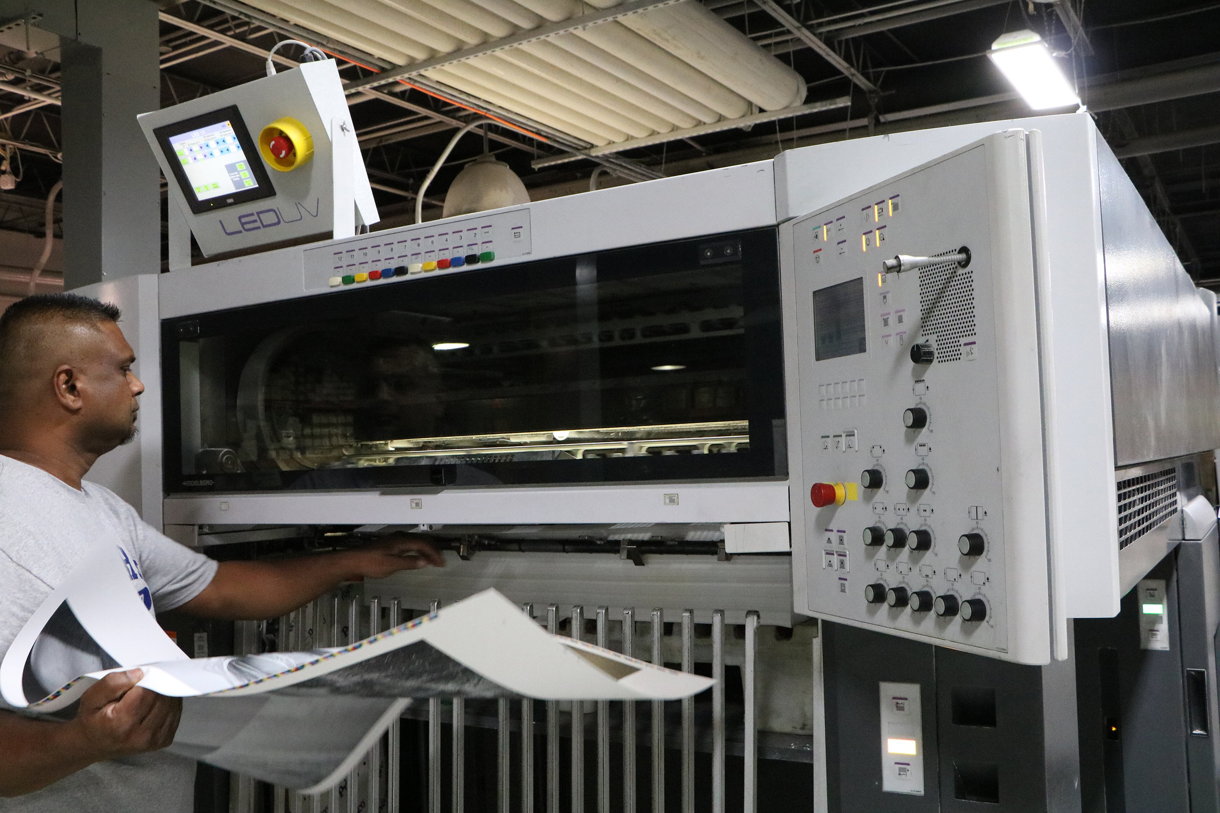 A Starnet press-team member pulls a dry sheet off of the press for checking.