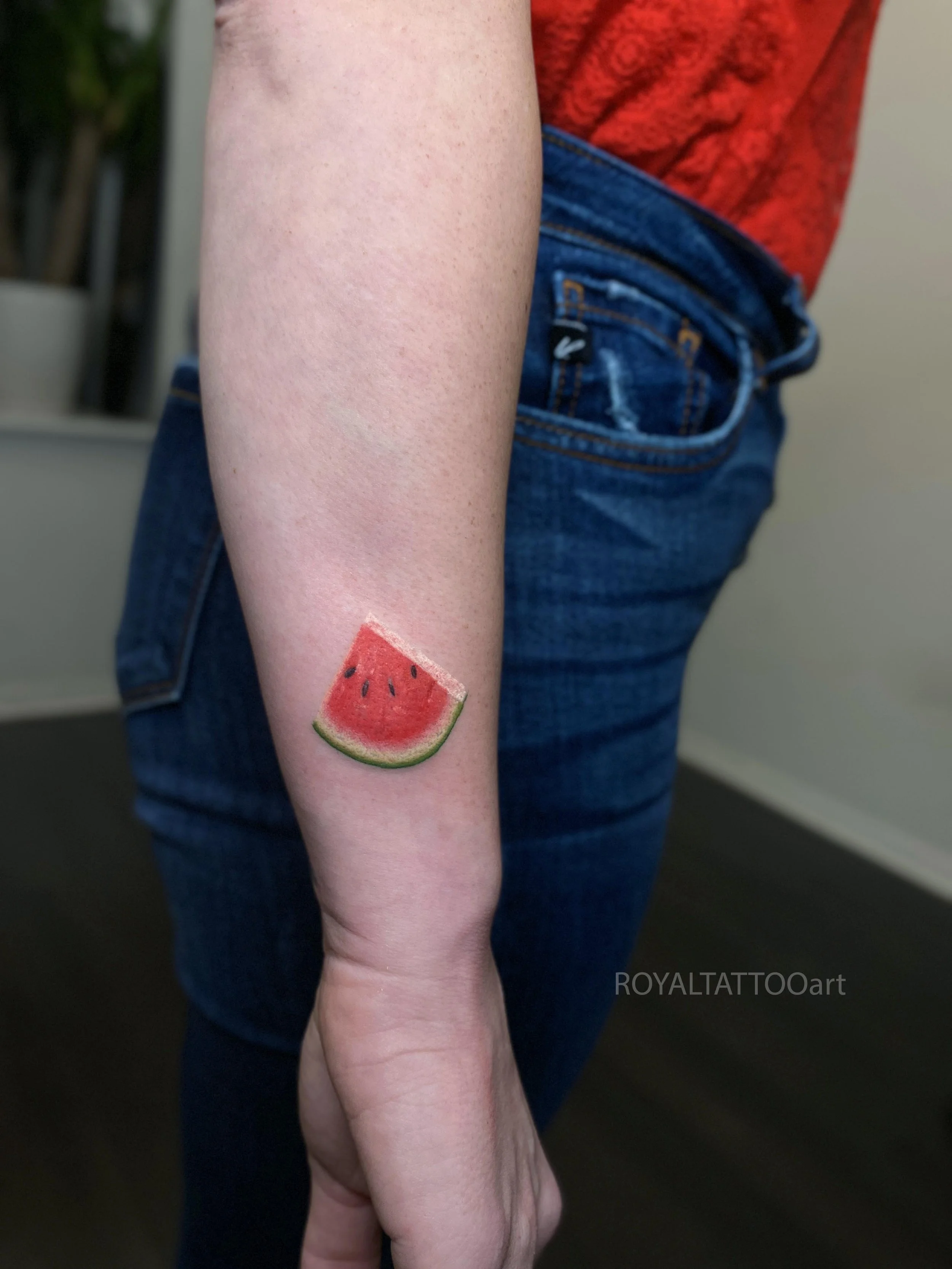Micro realism watermelon tattoo by Royal Jafarov at Royal Tattoo Art in Manhattan, NYC. A small realistic watermelon slice tattoo with bright color, clean detail, and smooth shading, designed for clients looking for micro realism tattoos in New York 