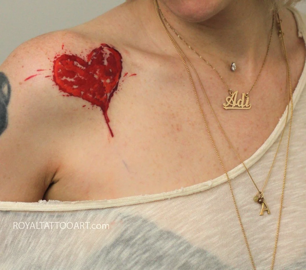 Red watercolor heart tattoo on chest and decolletage, romantic abstract ink design by Royal Jafarov at Royal Tattoo Art