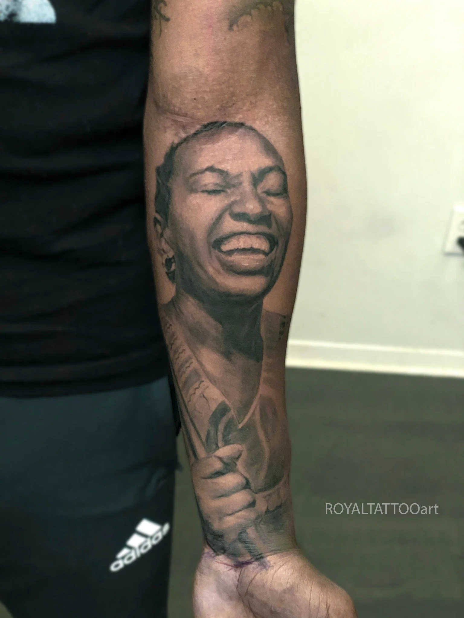 Realistic black and grey memorial portrait tattoo of a smiling mother on the forearm by Royal Tattoo Art NYC