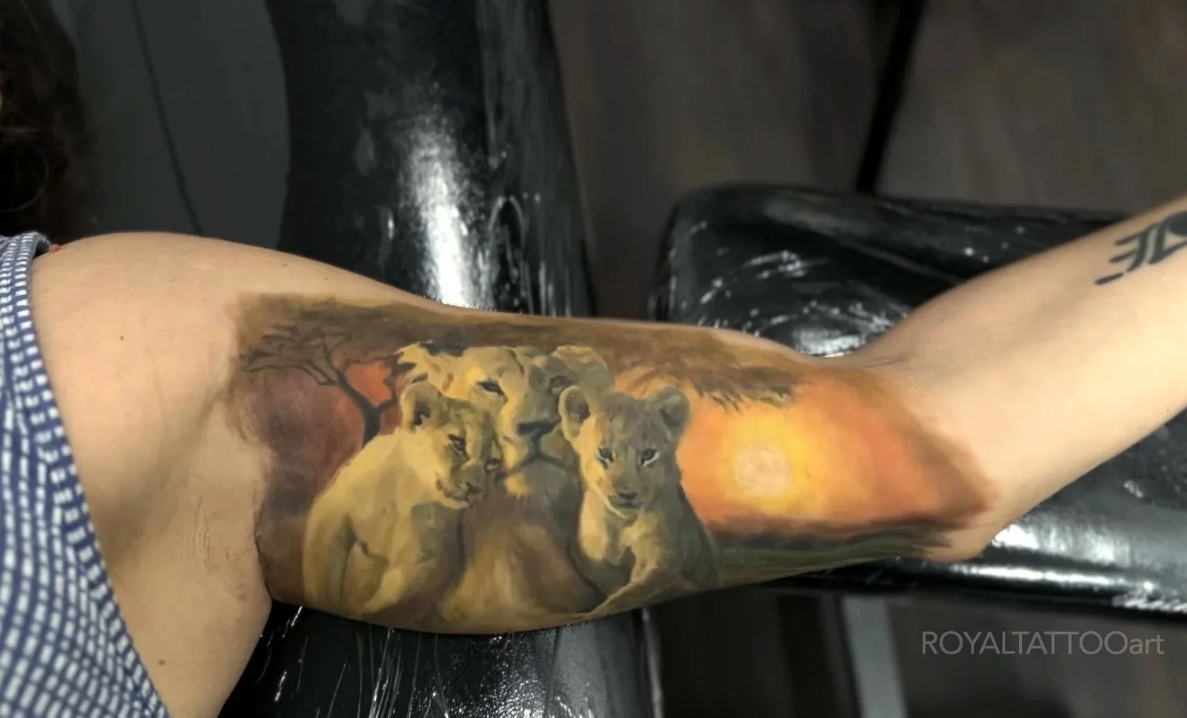 An abstract color tattoo with flowing golden and dark tones creating a dynamic, painterly effect across the forearm.