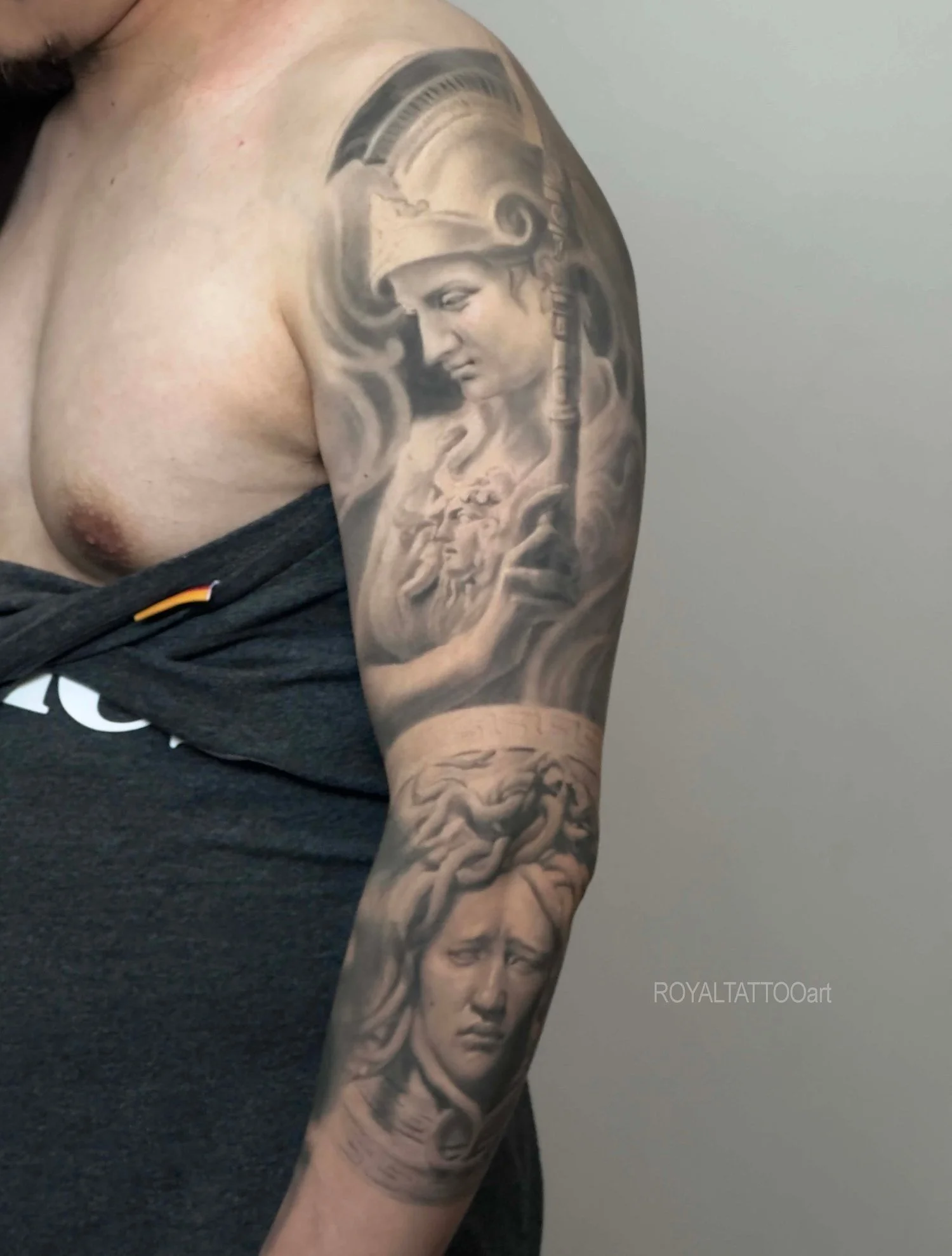 Black and grey Athena mythology sleeve tattoo featuring Greek goddess imagery, detailed armor, and realistic classical composition.