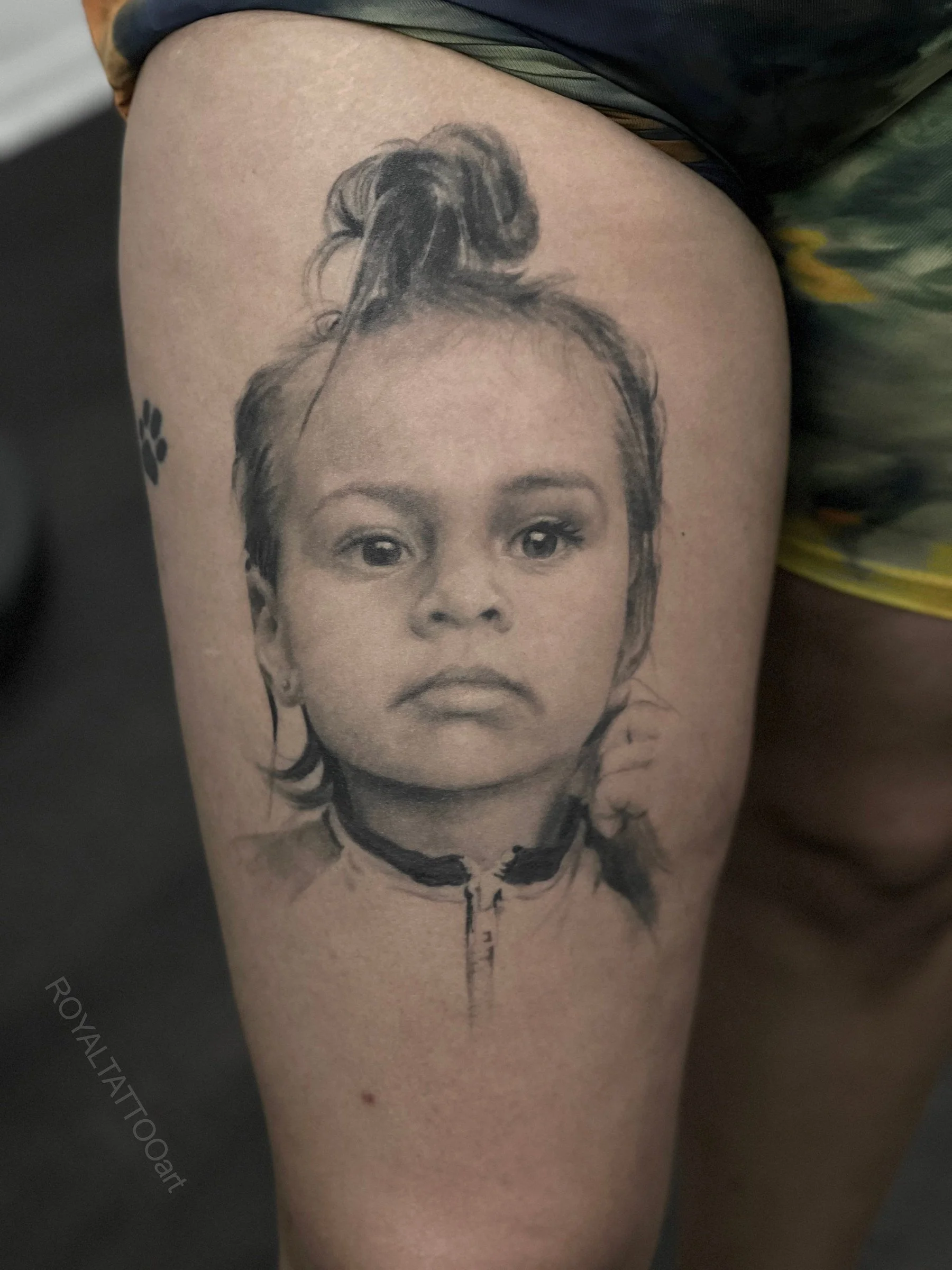 Black and grey child portrait tattoo on the thigh, created as a soft family portrait with realistic shading and delicate detail by Royal Jafarov in NYC.