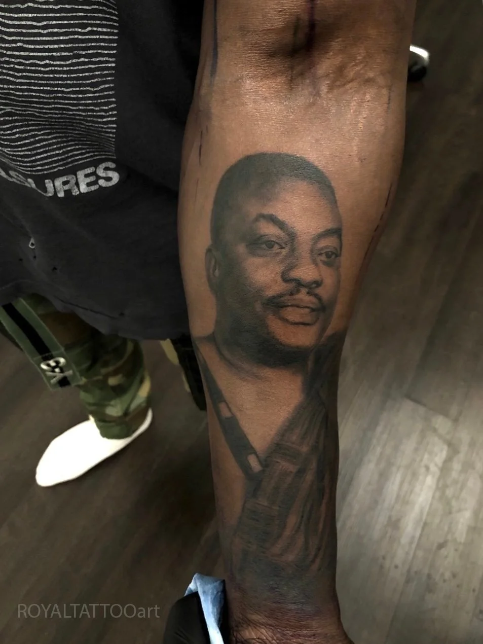 Black and grey realistic male portrait tattoo on the forearm, designed with smooth shading, strong likeness, and clean realism by Royal Jafarov in Manhattan.
