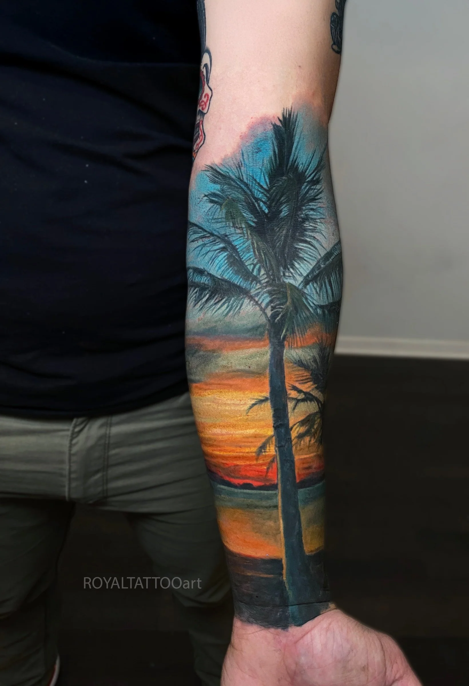 A tropical sunset scene with palm trees and vibrant hues, wrapping around the forearm in a dynamic full-sleeve design.