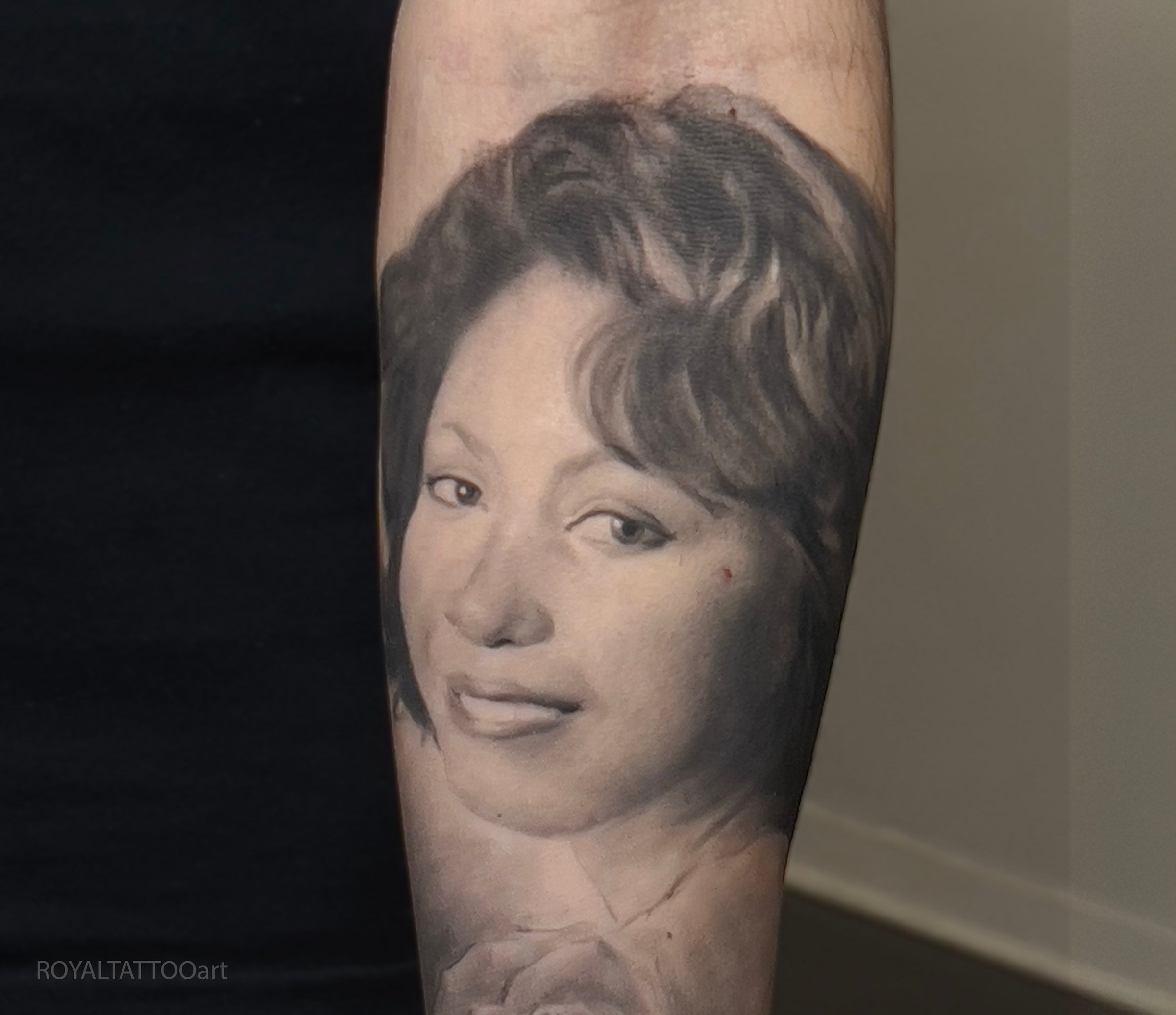 Black and grey mother portrait tattoo on the forearm, created as a realistic family tribute with soft shading and gentle detail by Royal Jafarov in NYC.