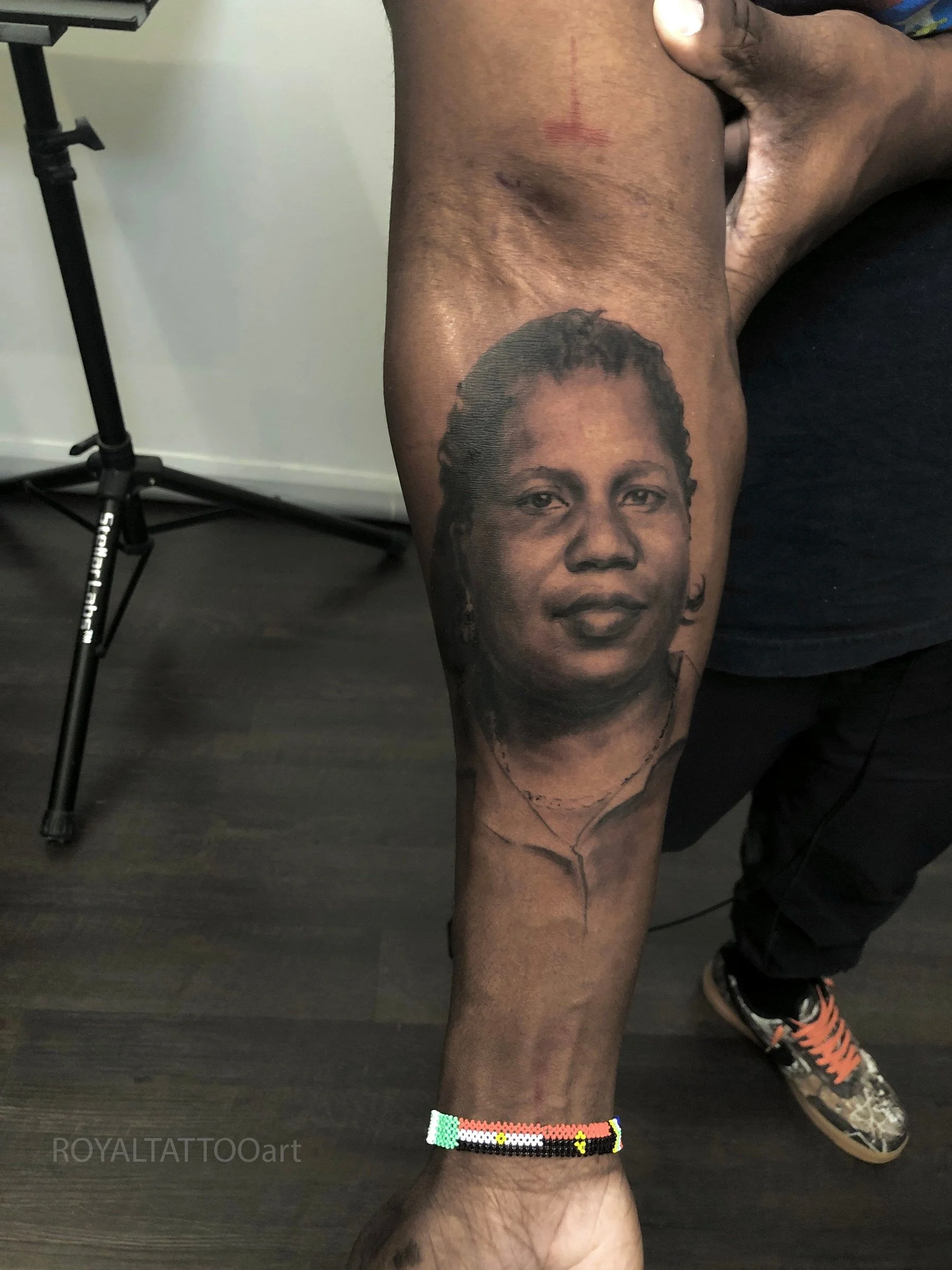 Black and grey mom portrait tattoo on the forearm, created with smooth realism and lifelike shading by Royal Jafarov in NYC.