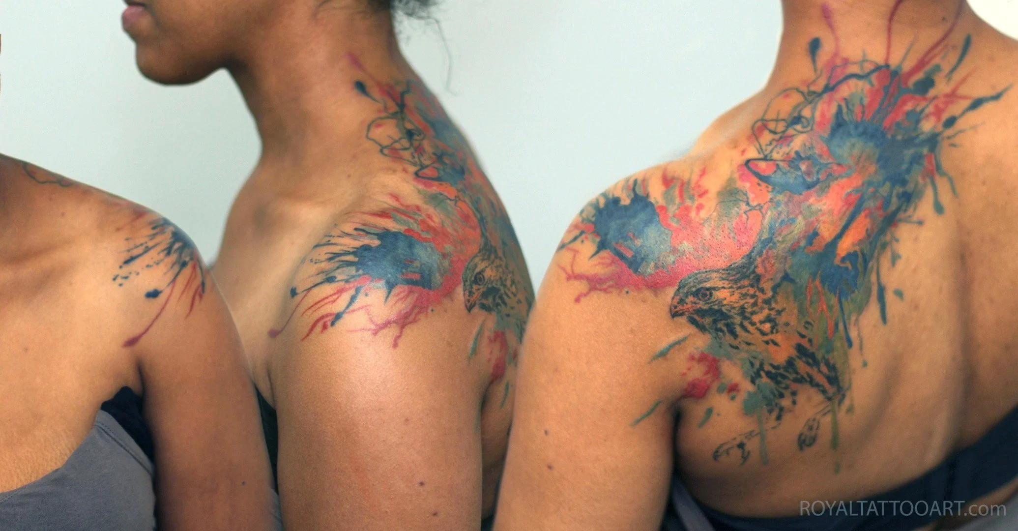 Colorful watercolor floral tattoo with blue and red flowers on upper back and shoulder, vibrant botanical ink art by Royal Jafarov at Royal Tattoo Art