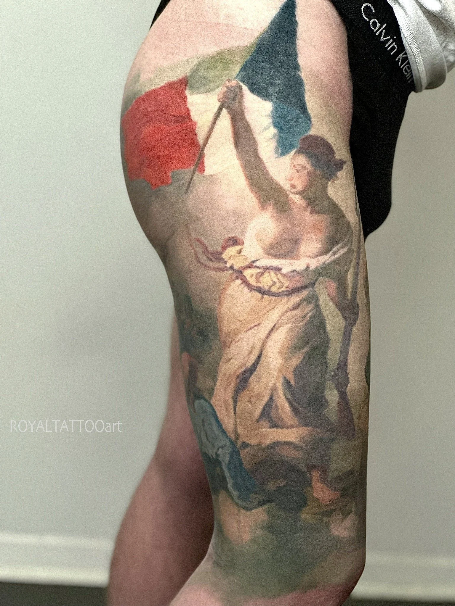 Liberty Leading the People fine art realism thigh tattoo inspired by Delacroix's revolutionary painting, done in NYC. Royal Tattoo Art transforms this iconic Romantic masterpiece into a bold and powerful thigh tattoo with exceptional color realism.