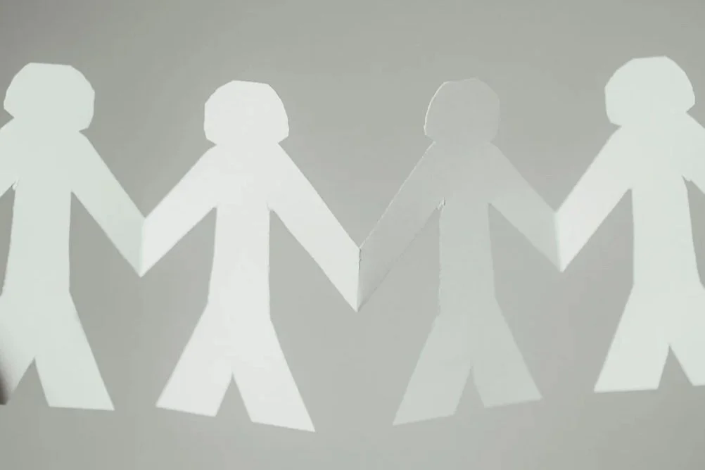 close up of a row of four simple paper dolls against a white background