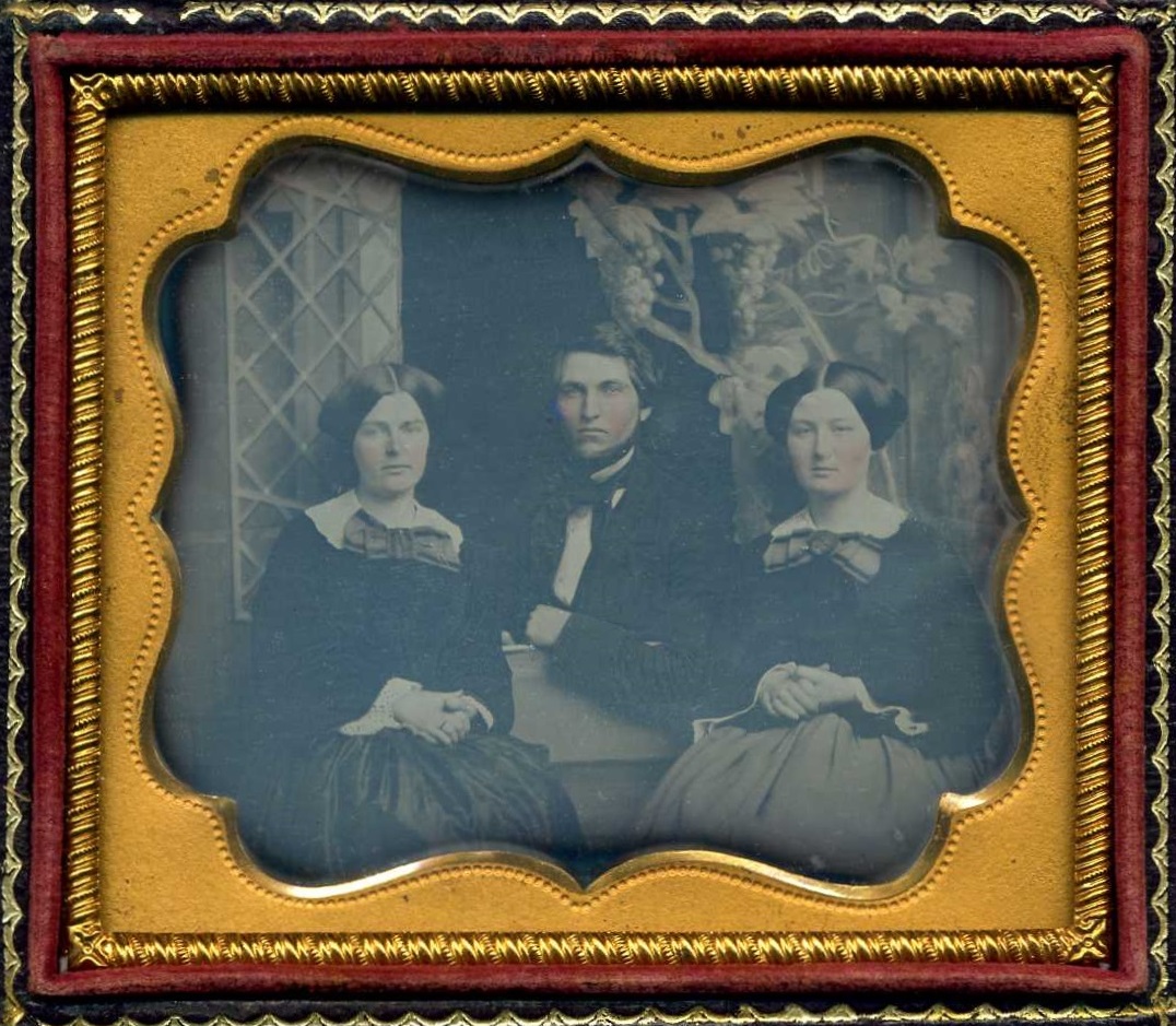 Two Women and a Man Sitting in Front of Backdrop